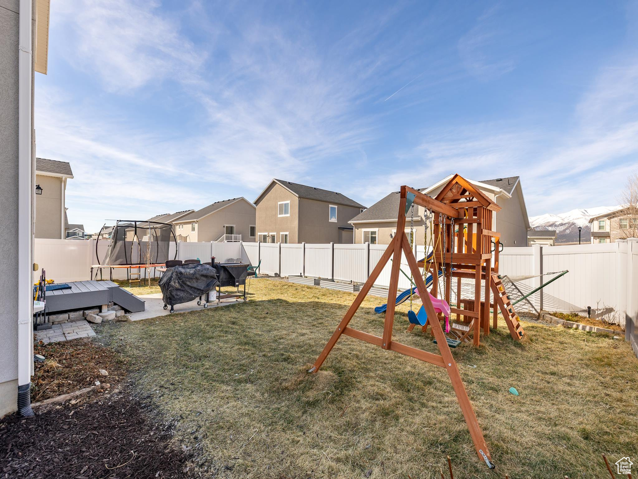 View of playground featuring a trampoline, a fenced backyard, and a lawn