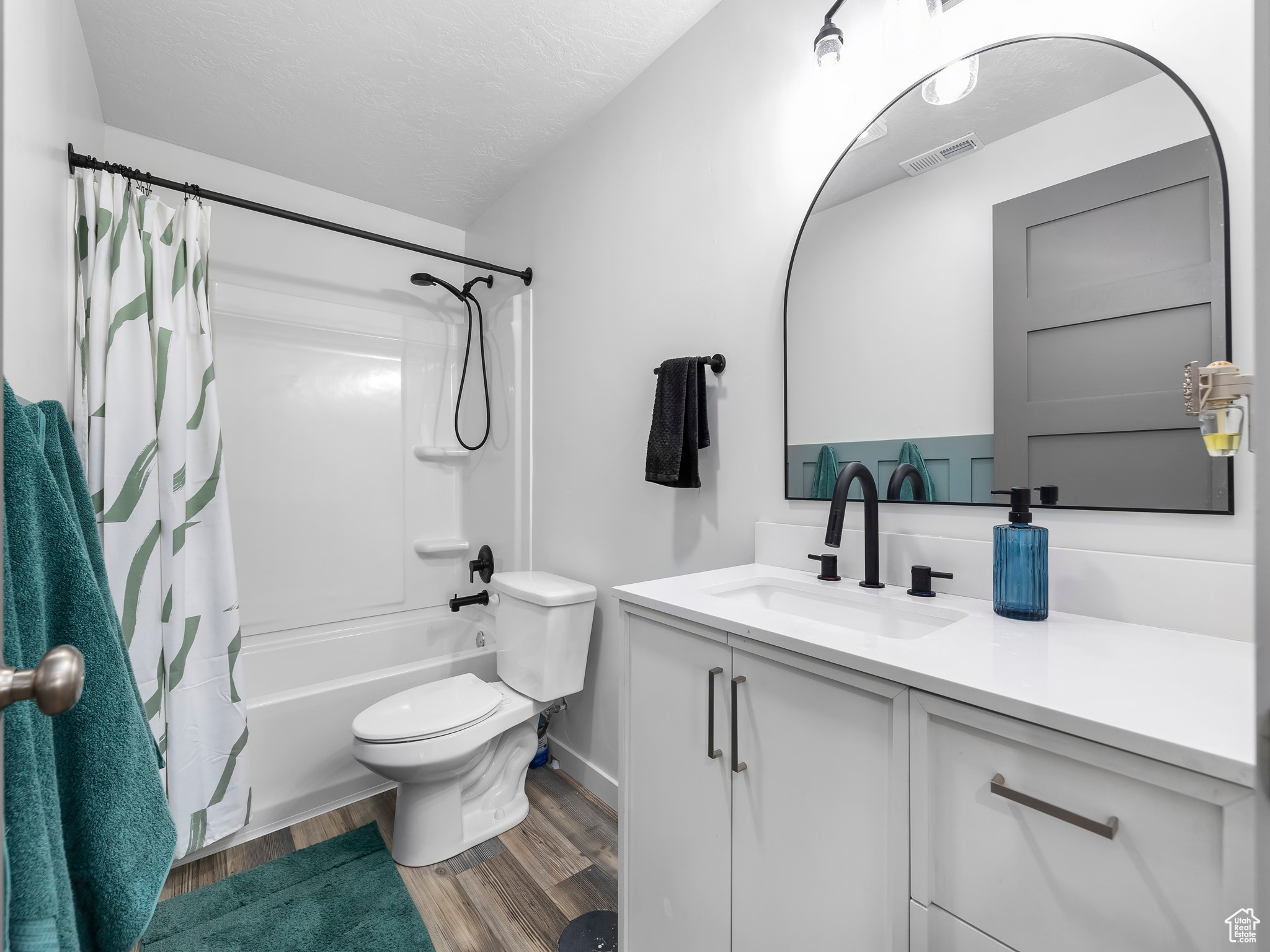 Bathroom featuring visible vents, shower / bath combo with shower curtain, toilet, wood finished floors, and vanity