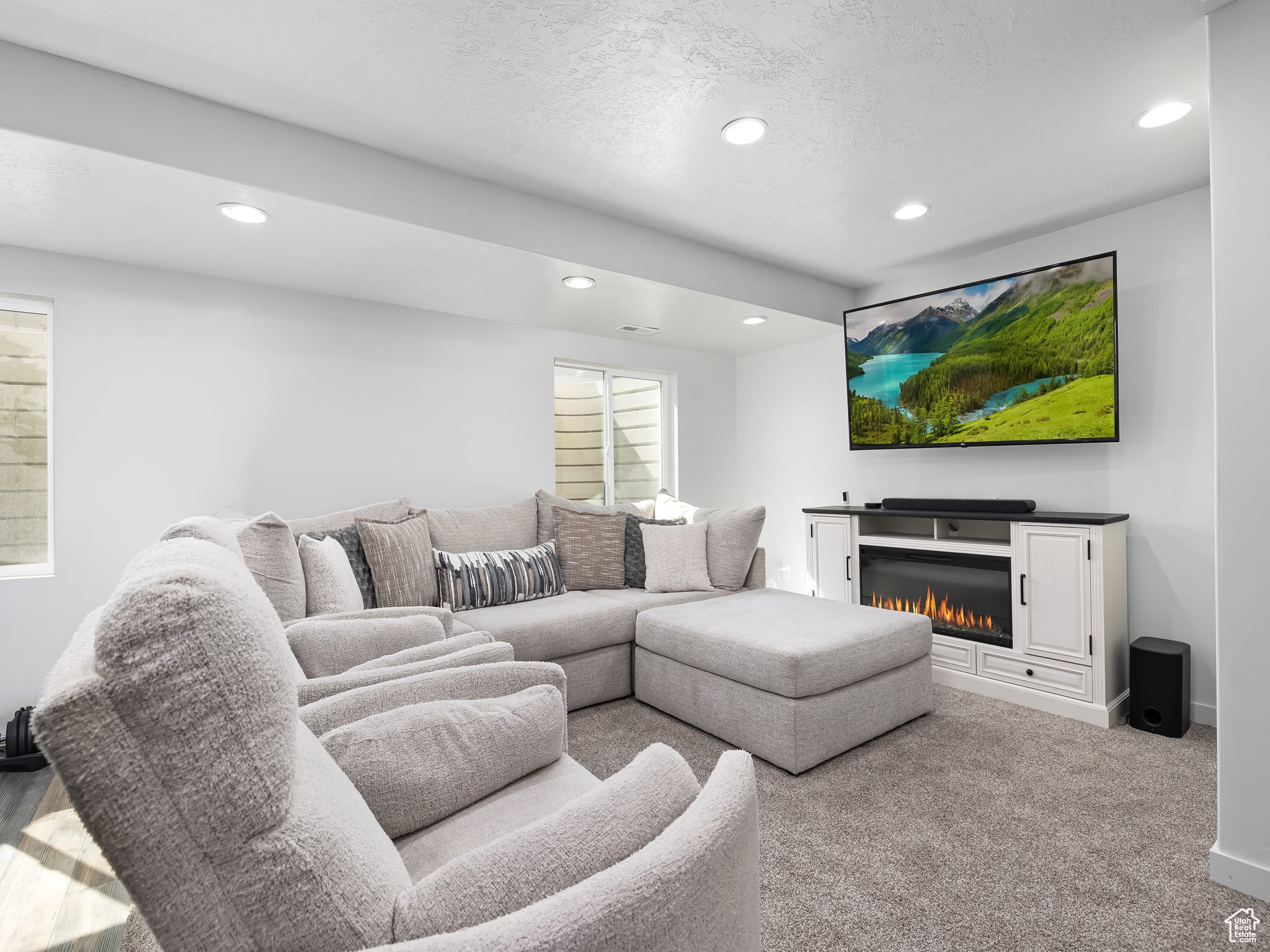 Carpeted living area with a glass covered fireplace, recessed lighting, and a textured ceiling
