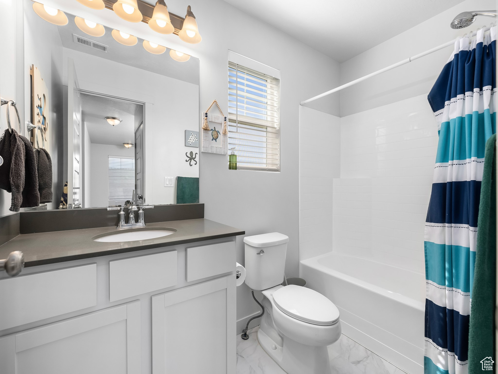 Full bathroom featuring visible vents, toilet, marble finish floor, shower / tub combo, and vanity