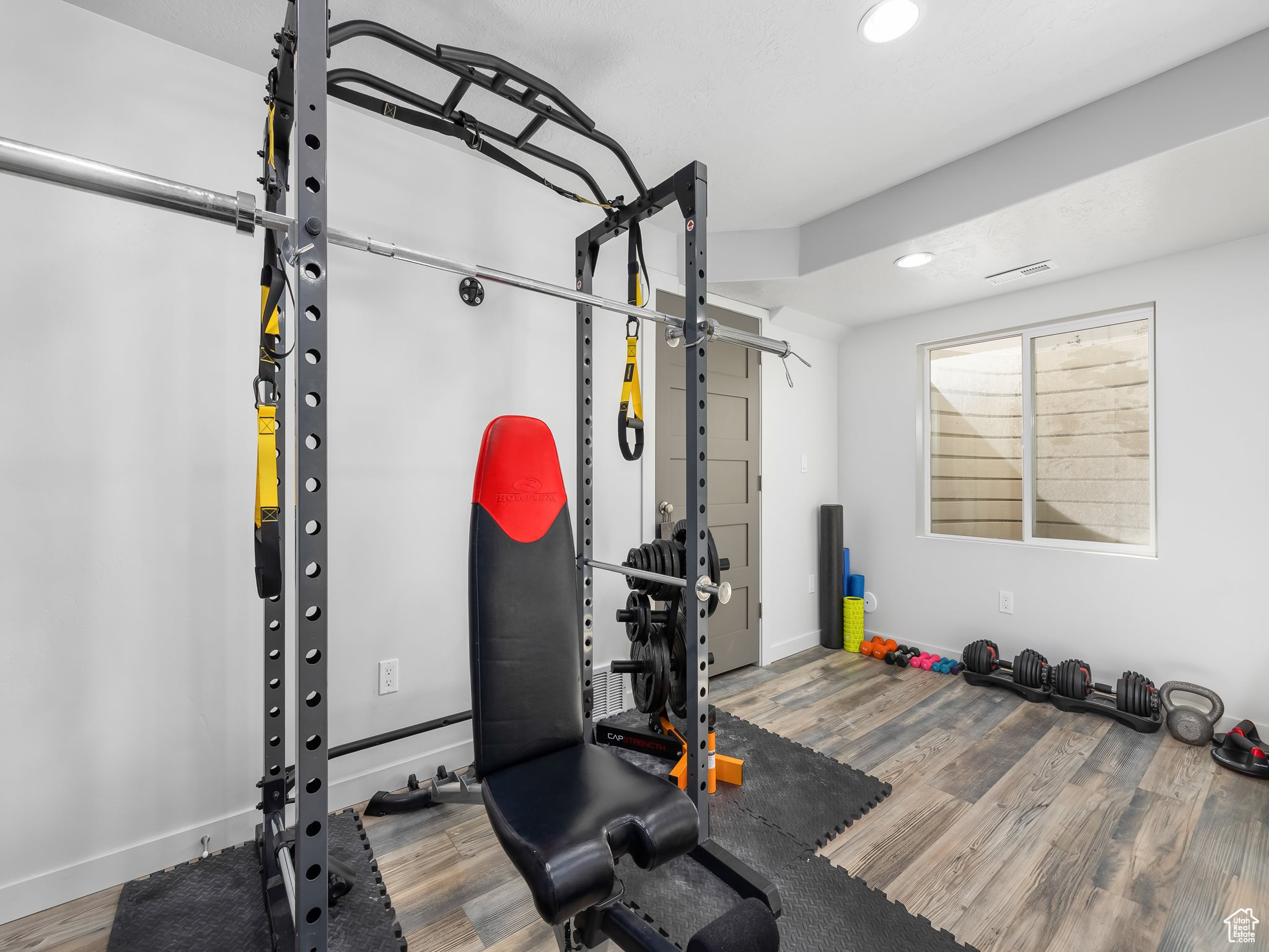 Exercise area featuring recessed lighting, visible vents, baseboards, and wood finished floors