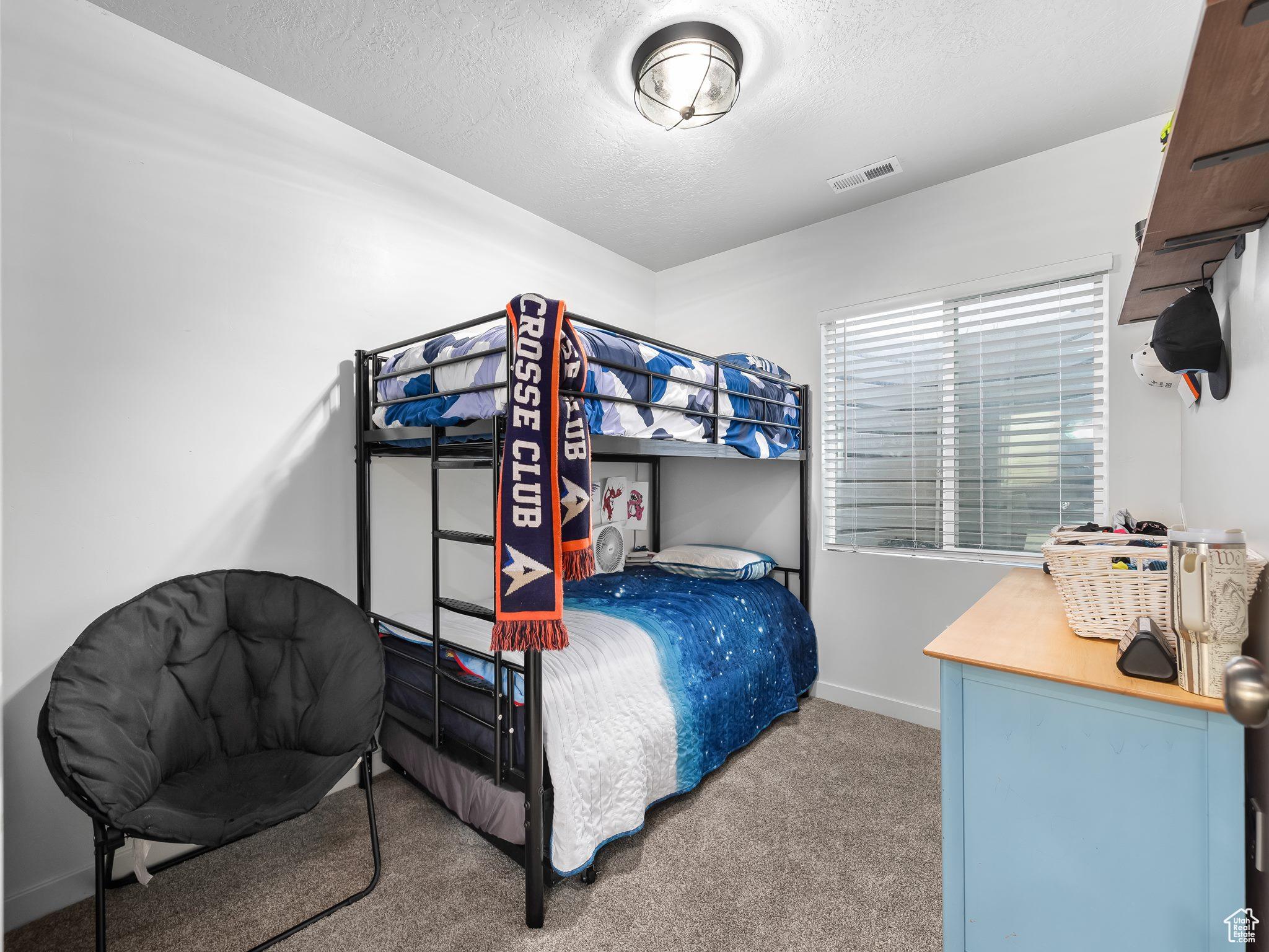 Carpeted bedroom with visible vents, a textured ceiling, and baseboards