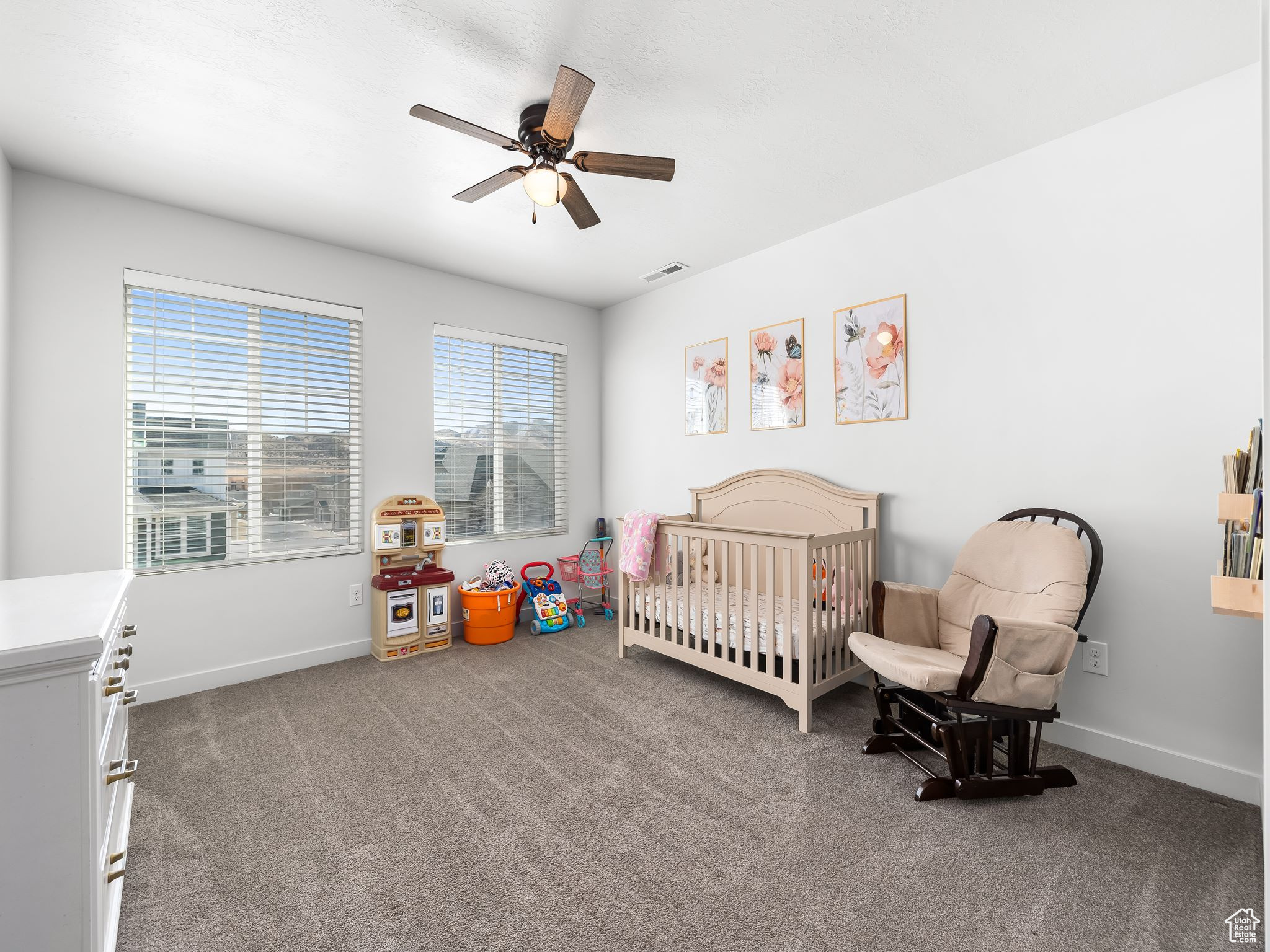 Bedroom featuring visible vents, baseboards, carpet, a ceiling fan, and a nursery area