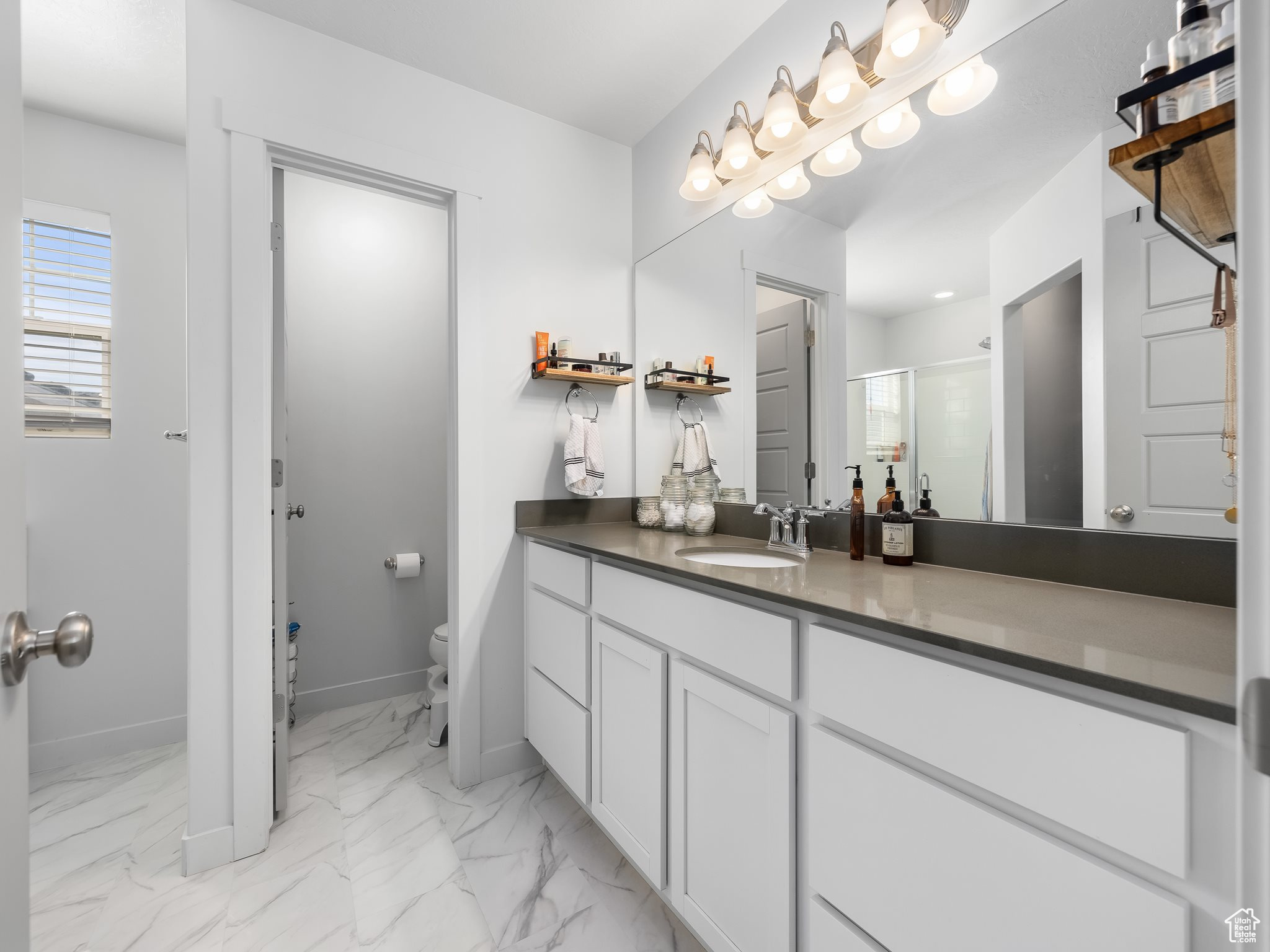 Bathroom featuring vanity, baseboards, a shower stall, toilet, and marble finish floor