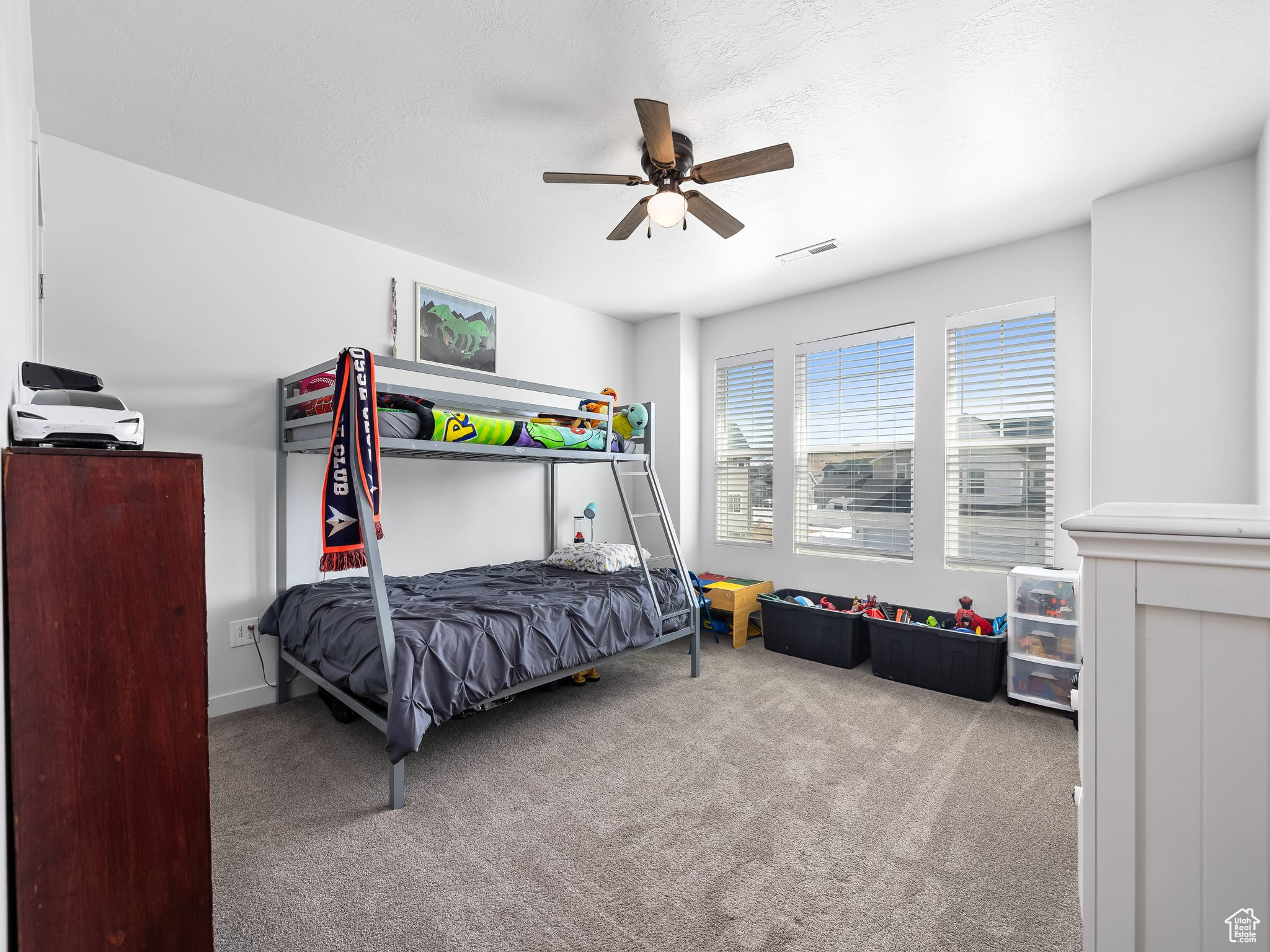 Carpeted bedroom featuring visible vents and a ceiling fan