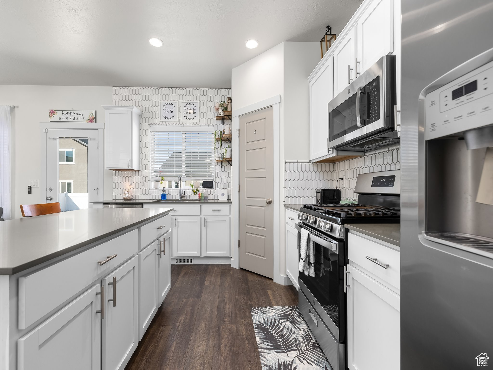 Kitchen featuring recessed lighting, white cabinets, appliances with stainless steel finishes, and dark wood-style flooring