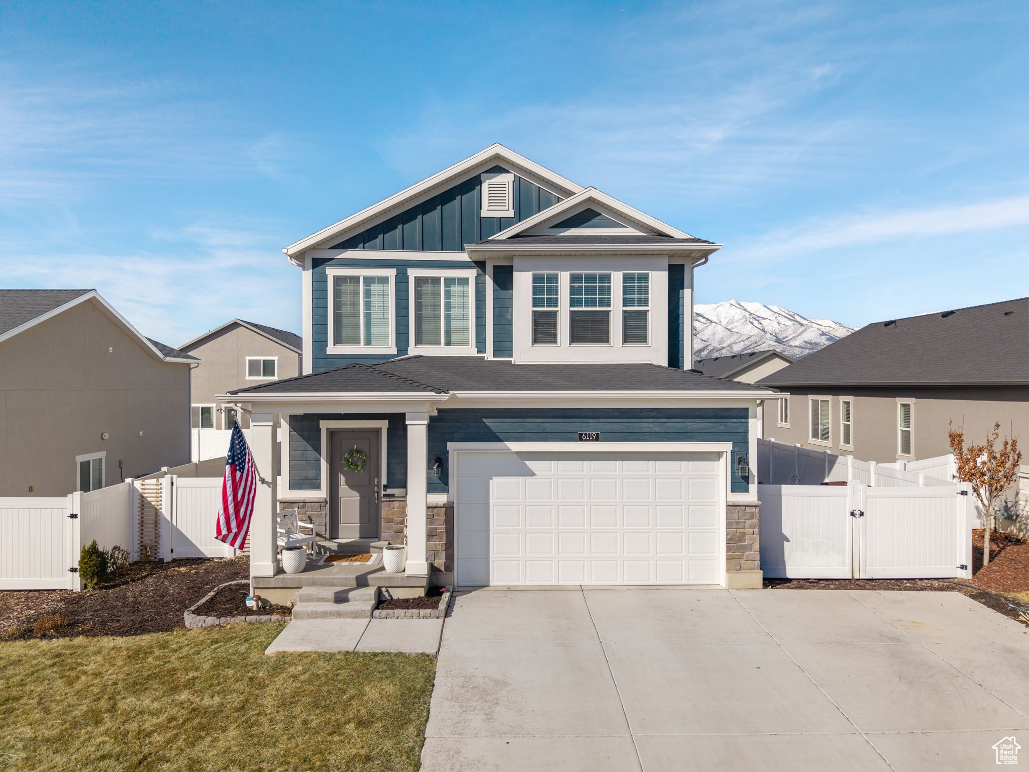 View of front of property featuring a gate, fence, board and batten siding, and driveway
