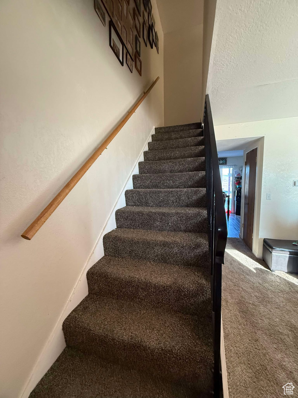 Stairs with baseboards, carpet floors, and a textured ceiling
