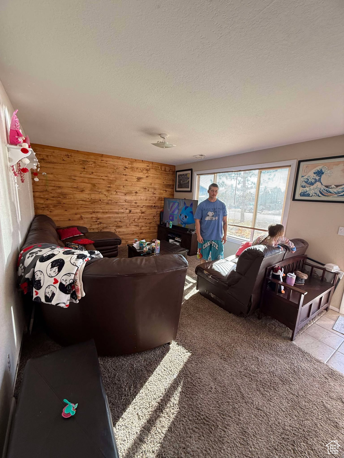 Carpeted living room featuring wooden walls and a textured ceiling