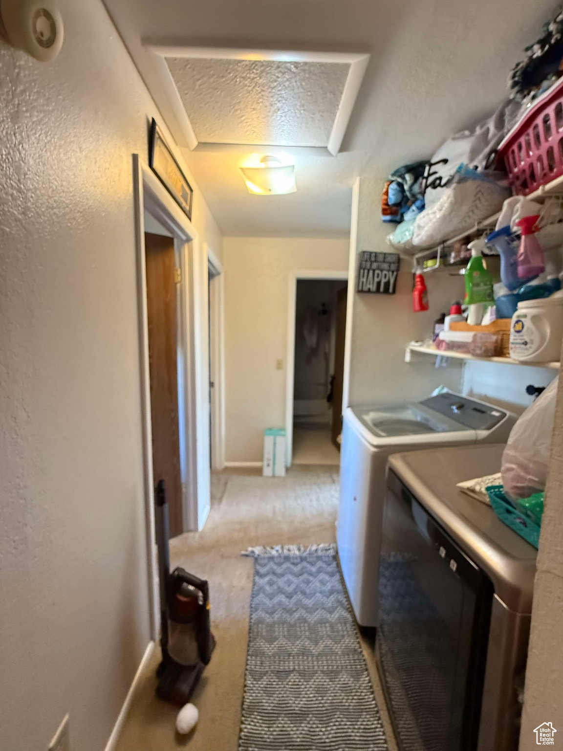 Laundry area featuring washer and clothes dryer, light colored carpet, attic access, laundry area, and a textured ceiling