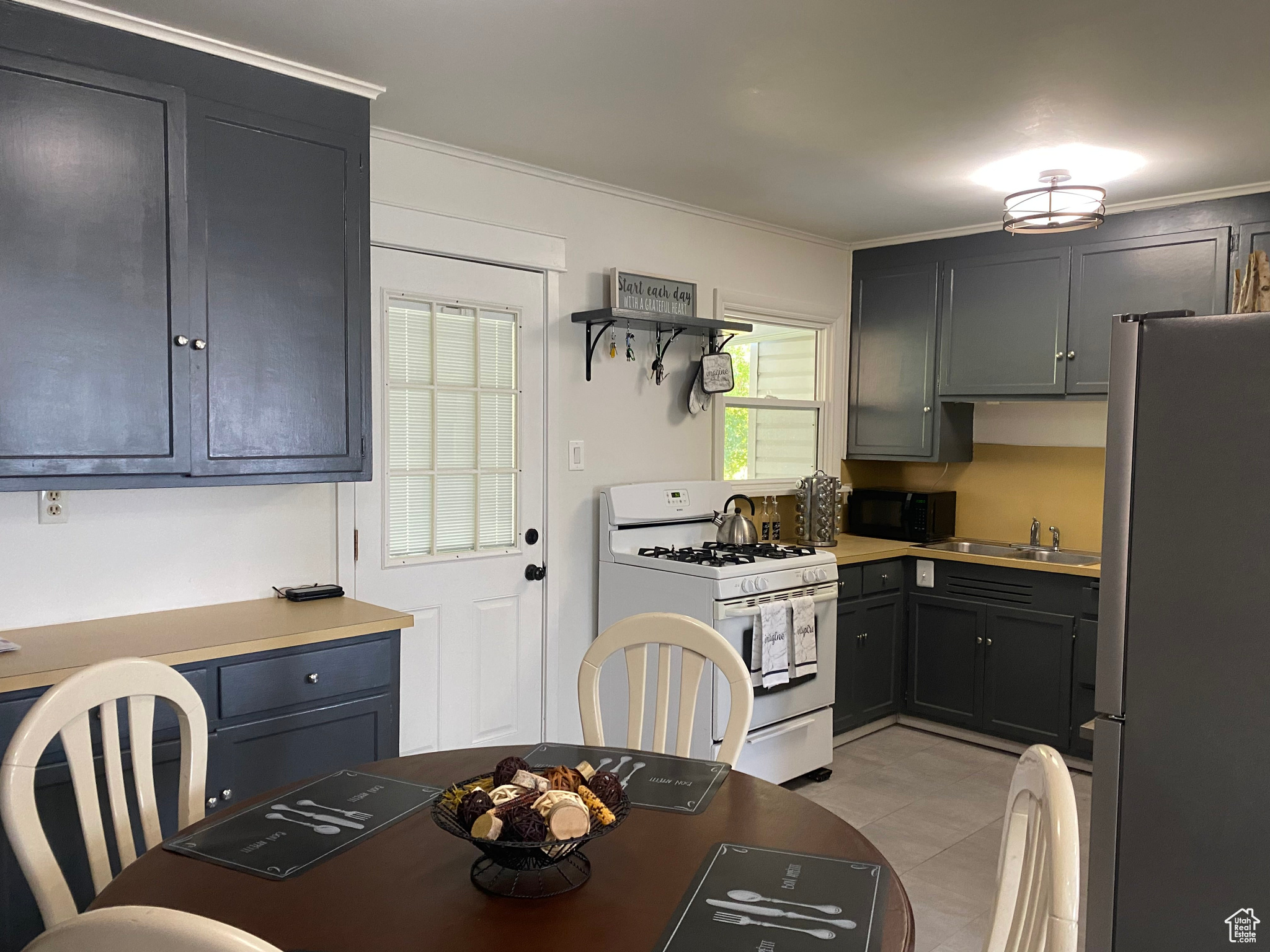 Kitchen featuring gas range gas stove, freestanding refrigerator, a sink, black microwave, and crown molding