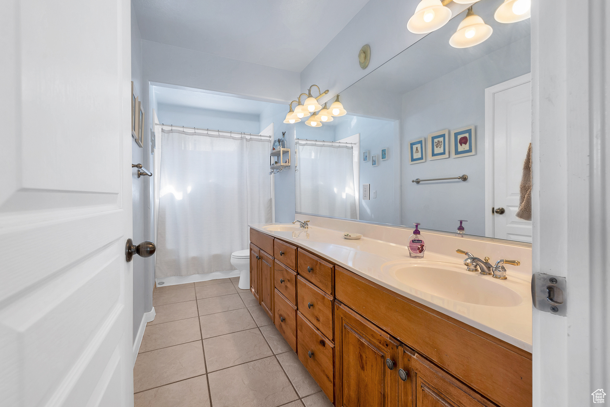 Bathroom with tile patterned floors, double vanity, toilet, and a sink