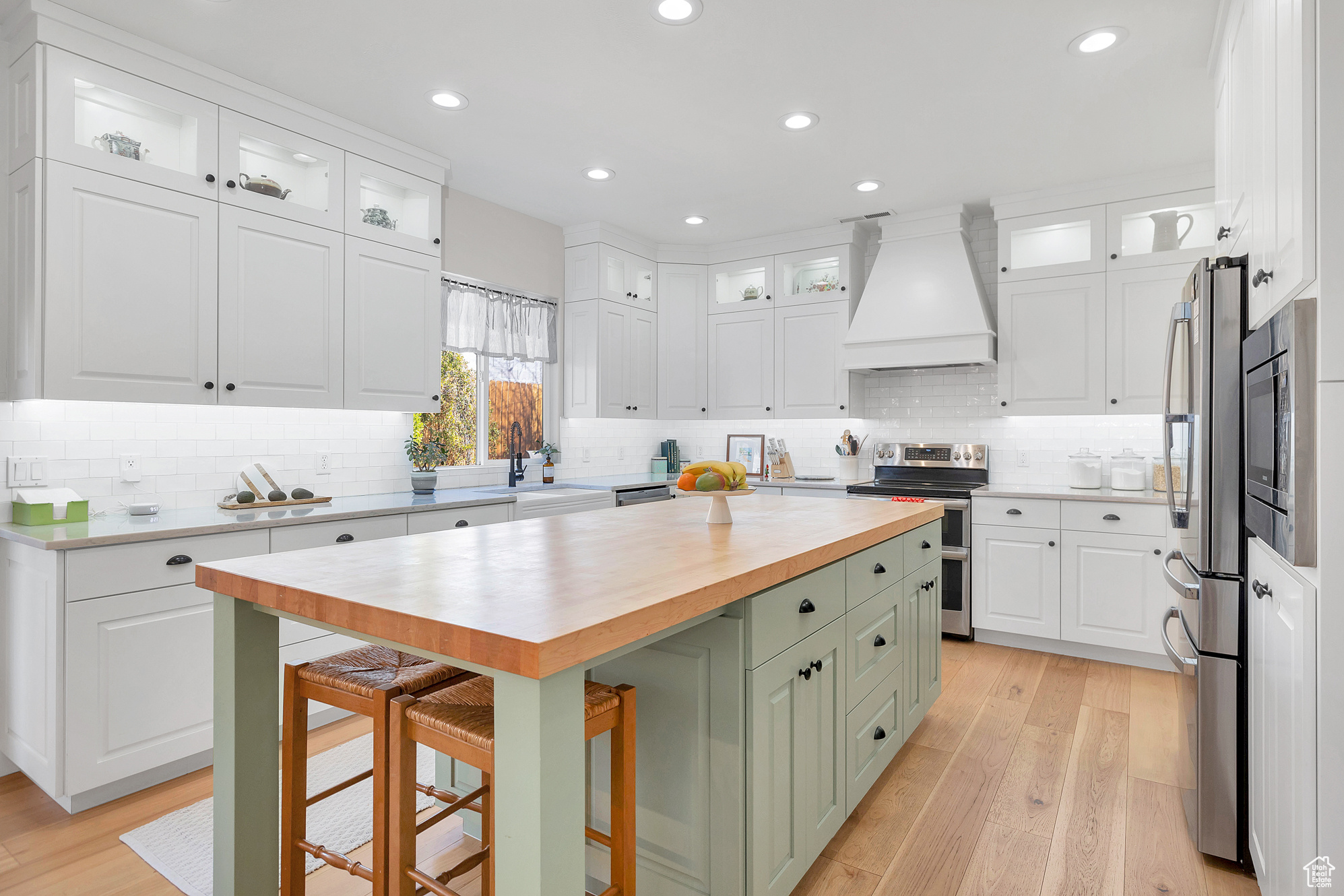 Kitchen with double oven range, premium range hood, a sink, wood counters, and white cabinetry