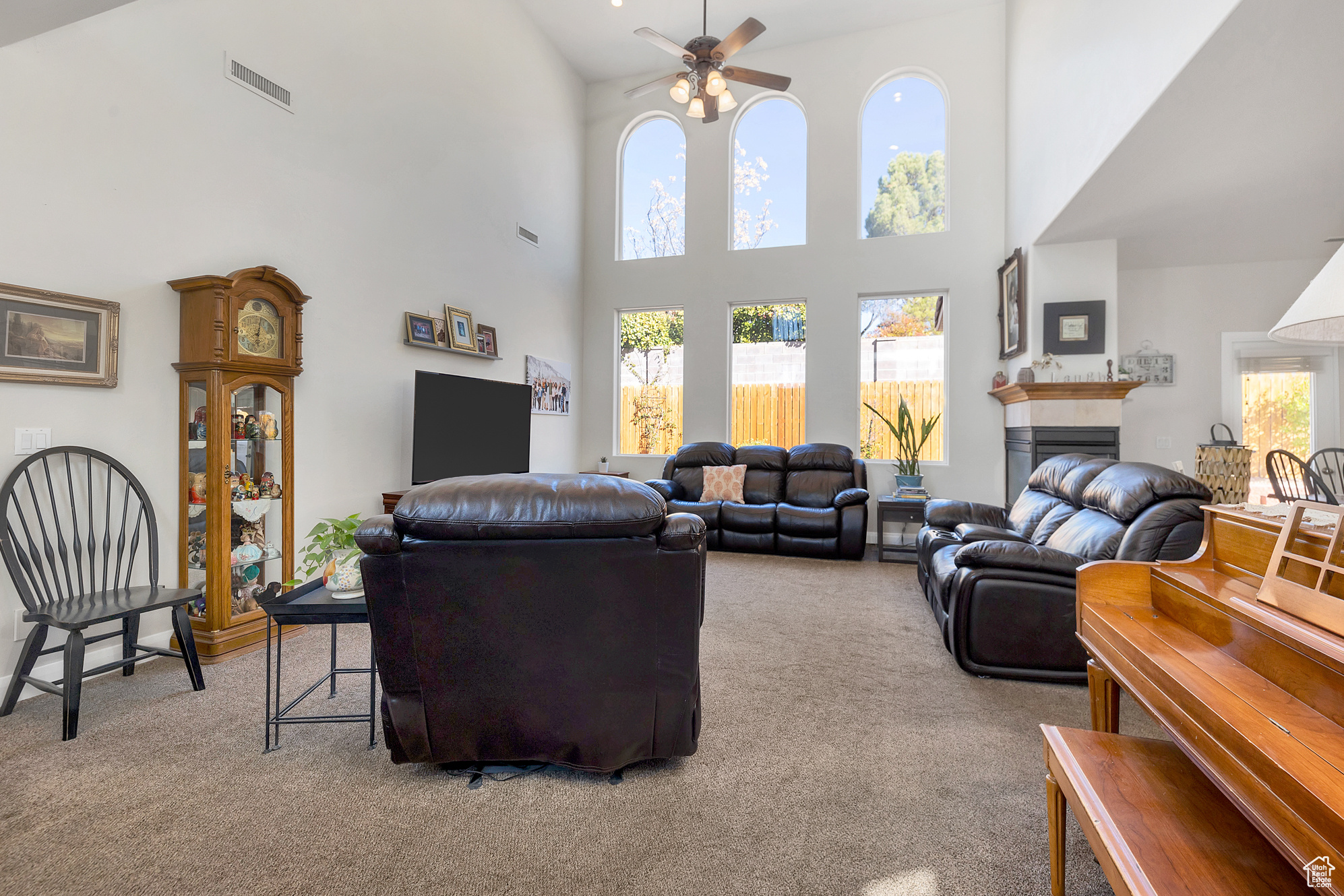 Carpeted living room with visible vents, a healthy amount of sunlight, a ceiling fan, and a tile fireplace