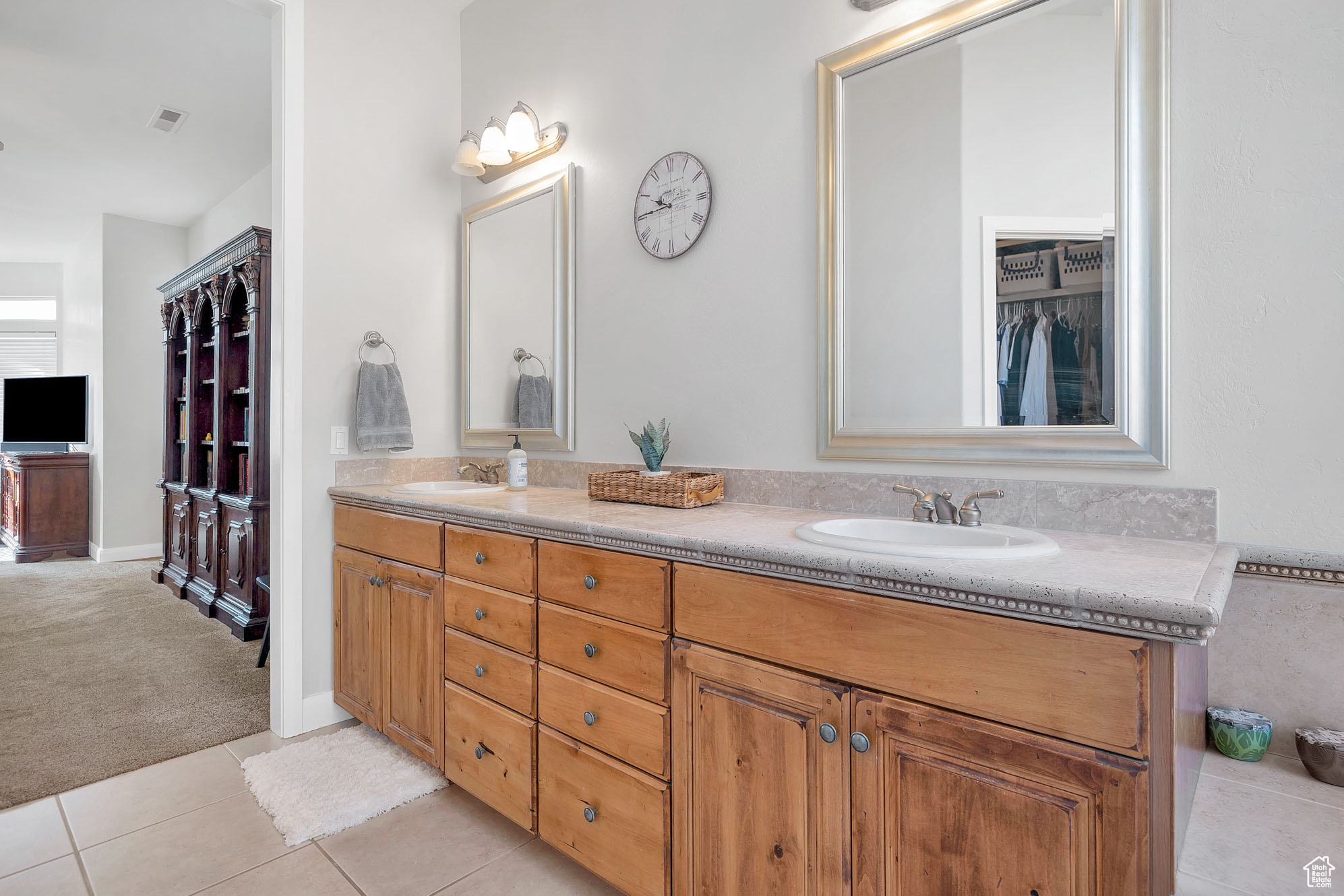 Bathroom featuring a sink, double vanity, a spacious closet, and tile patterned floors