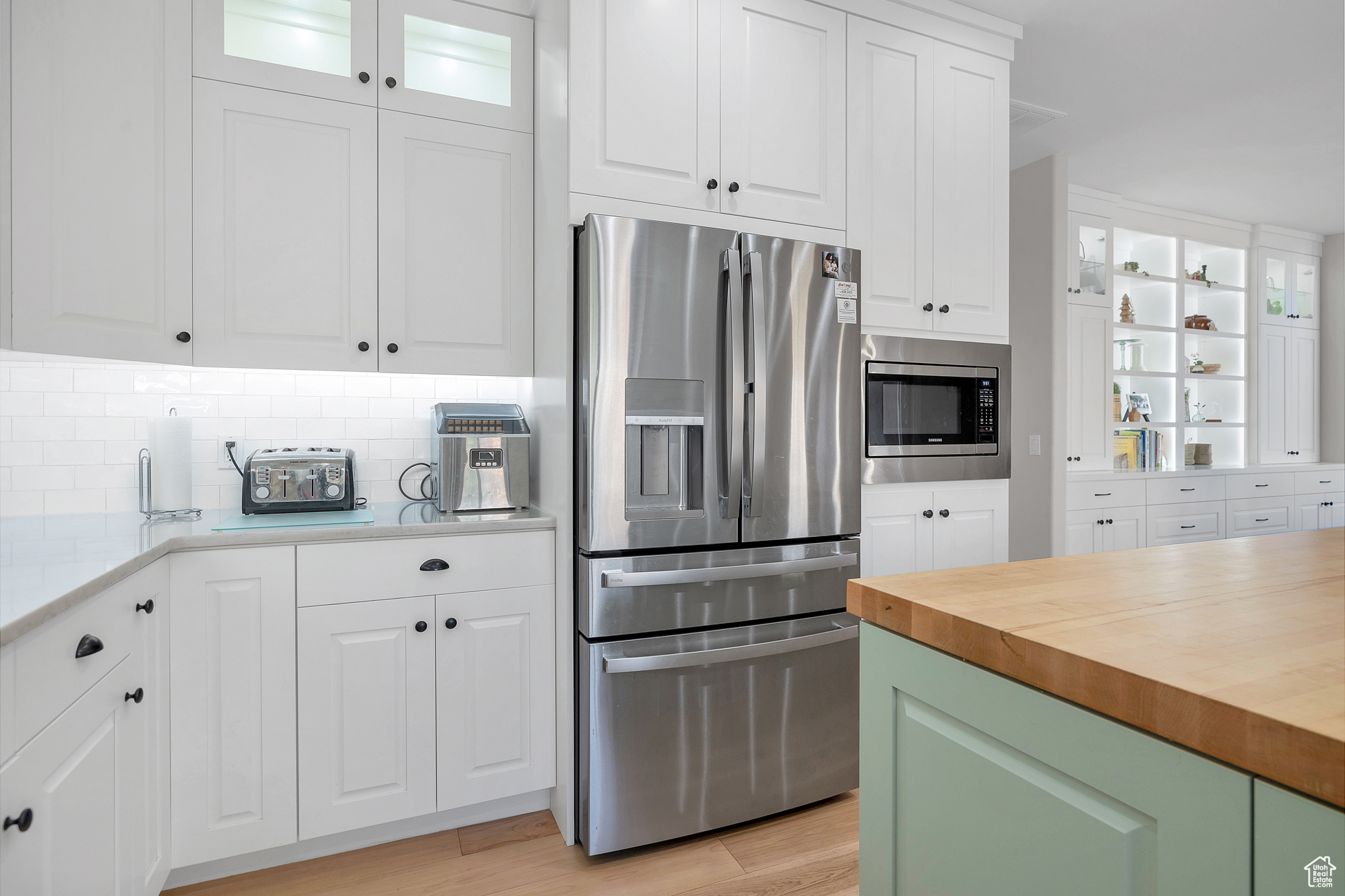 Kitchen featuring decorative backsplash, butcher block counters, white cabinetry, and stainless steel appliances