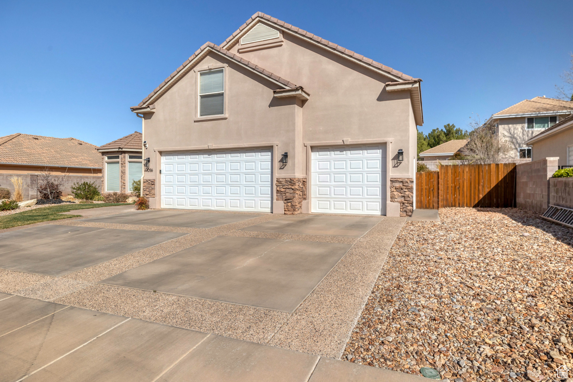 Traditional-style home with fence, driveway, stucco siding, a garage, and stone siding