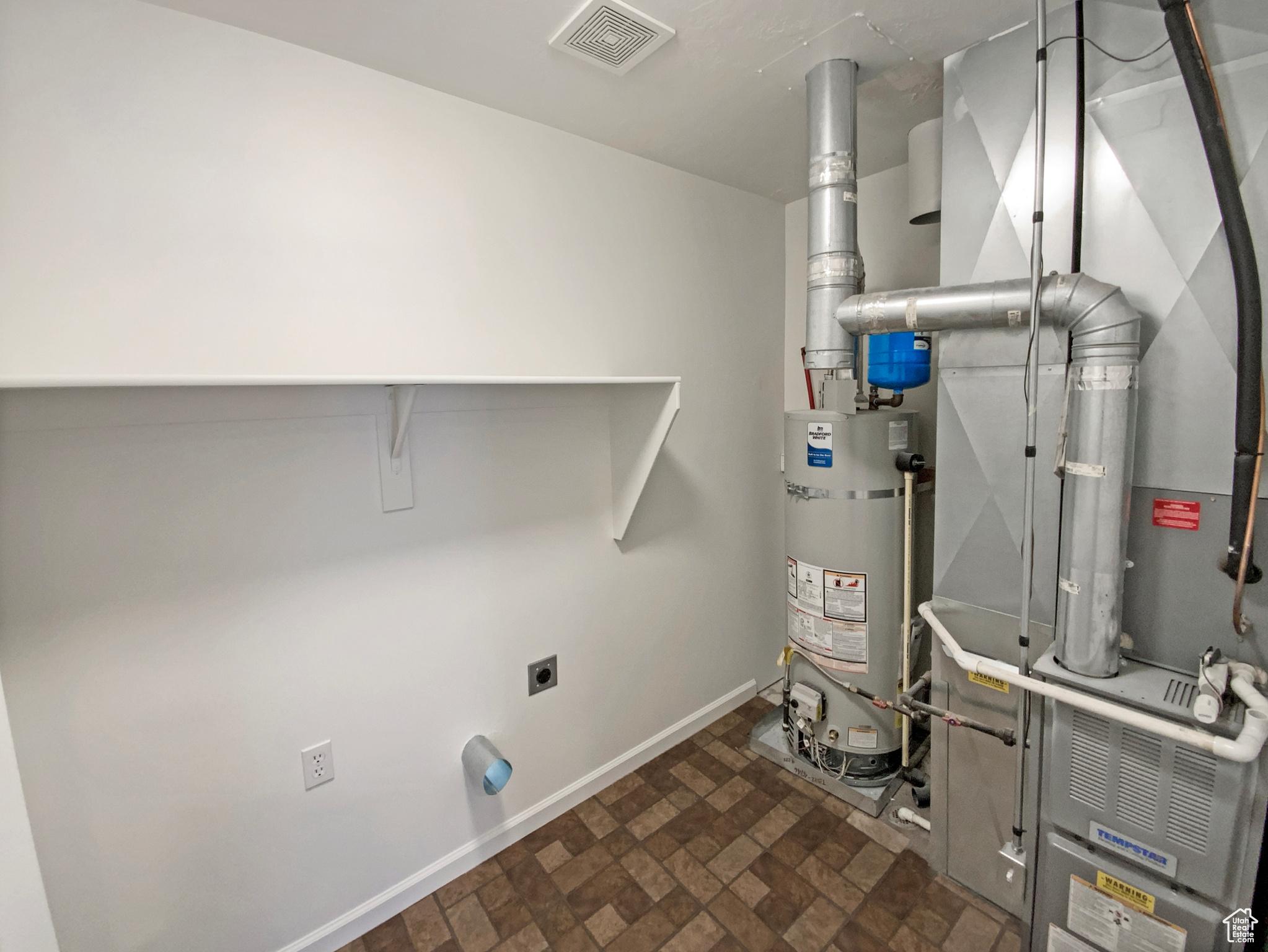Utilities with strapped water heater, heating unit, and visible vents