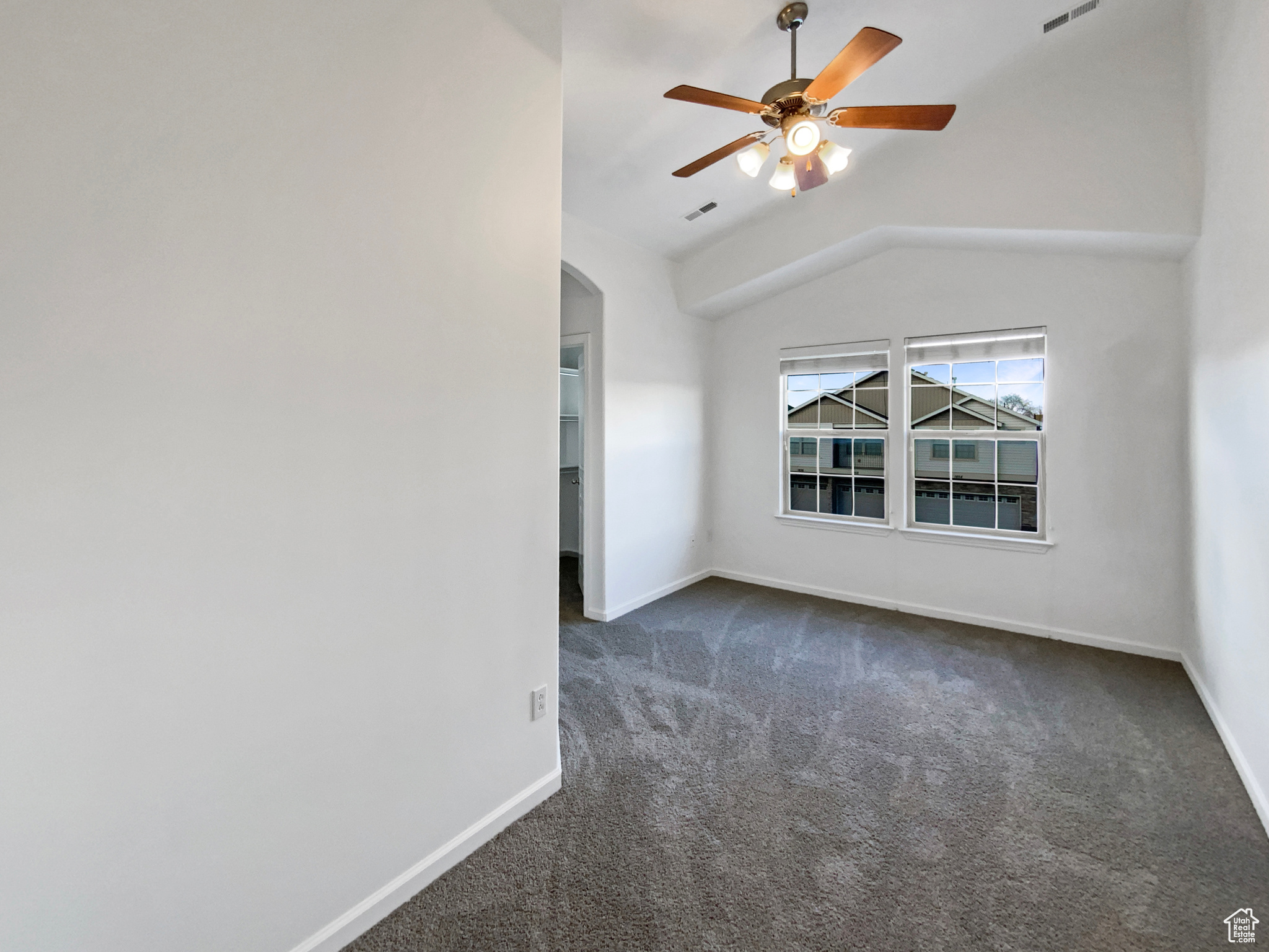 Spare room with arched walkways, baseboards, and dark colored carpet