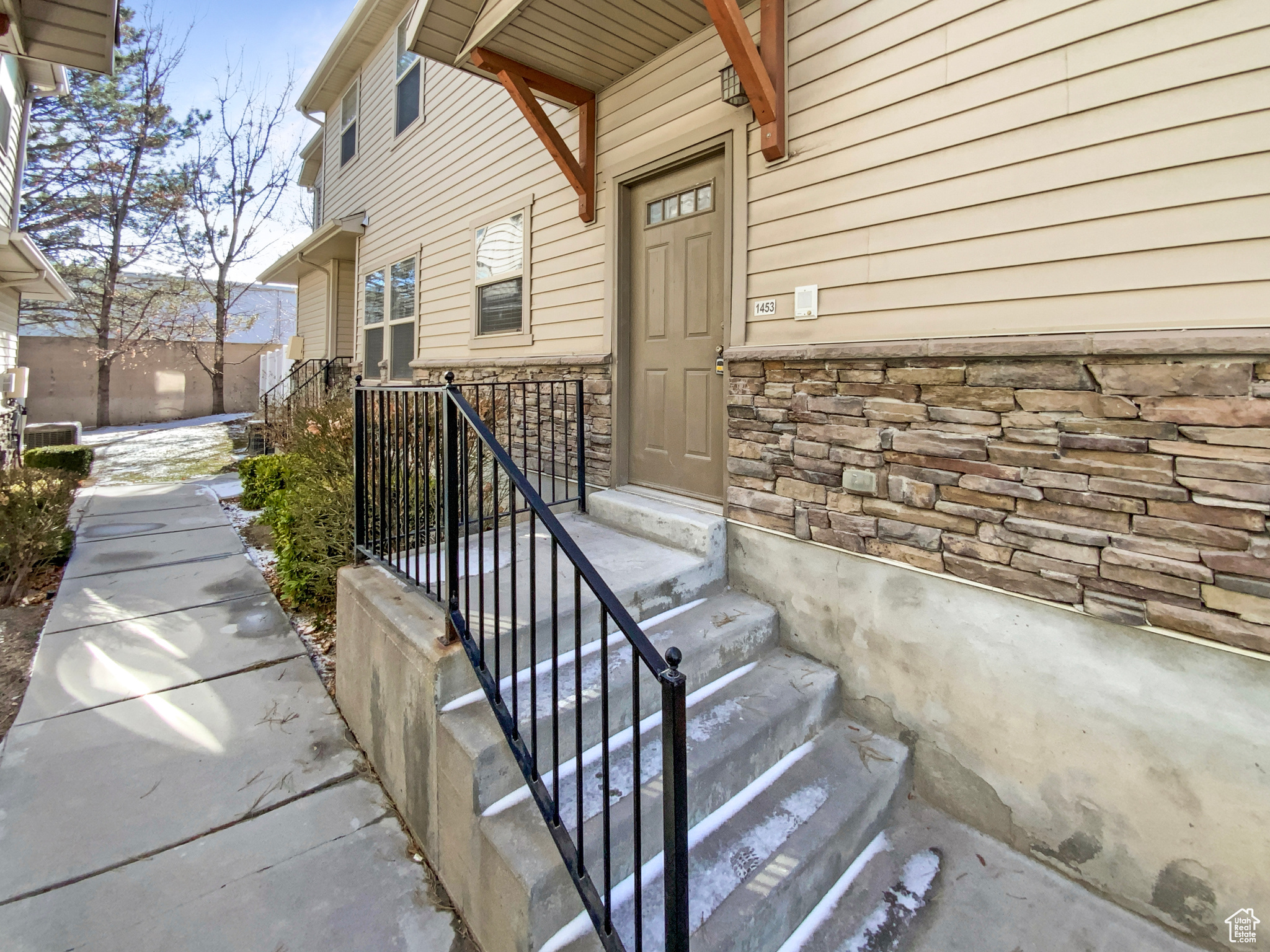 Entrance to property with stone siding and central air condition unit