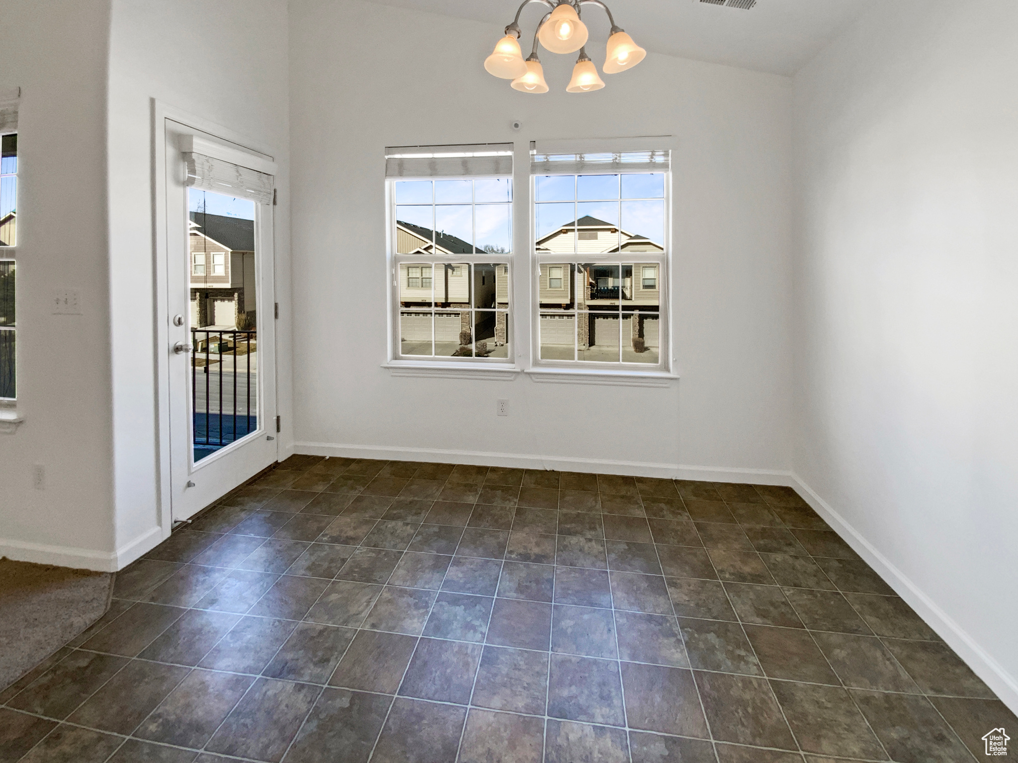 Unfurnished dining area with vaulted ceiling, a notable chandelier, and baseboards