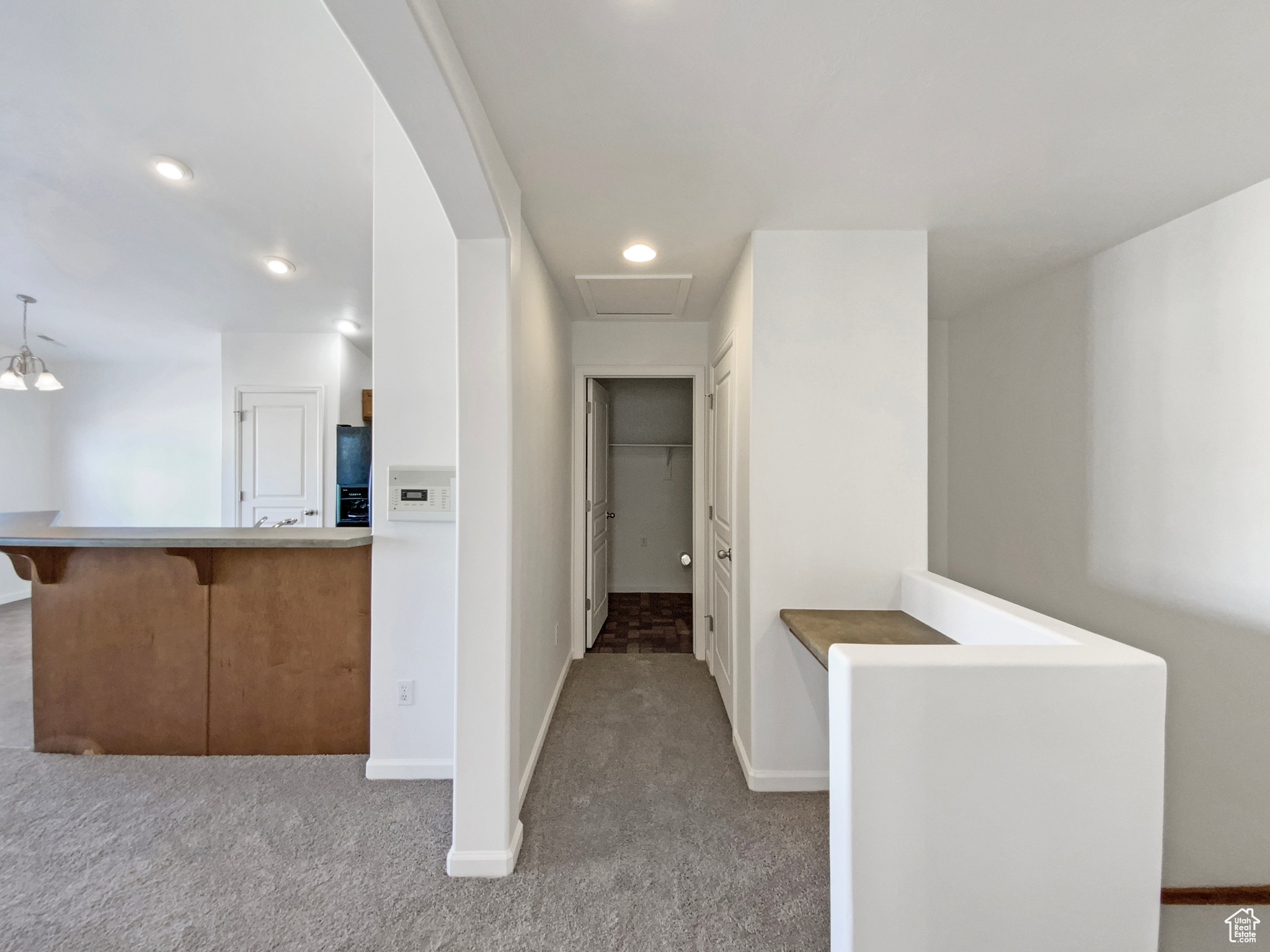 Corridor featuring baseboards, attic access, and carpet flooring