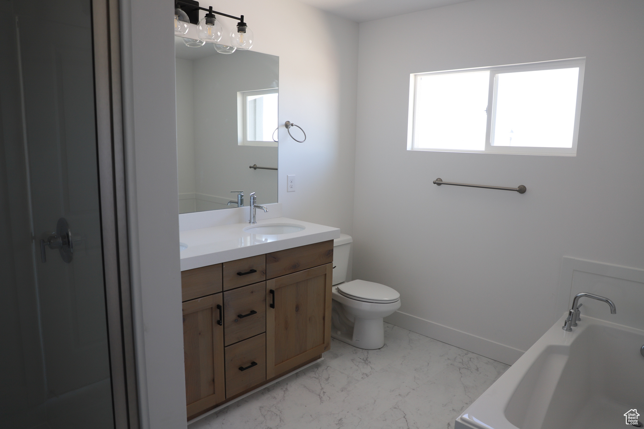 Full bath with baseboards, a sink, toilet, marble finish floor, and a washtub