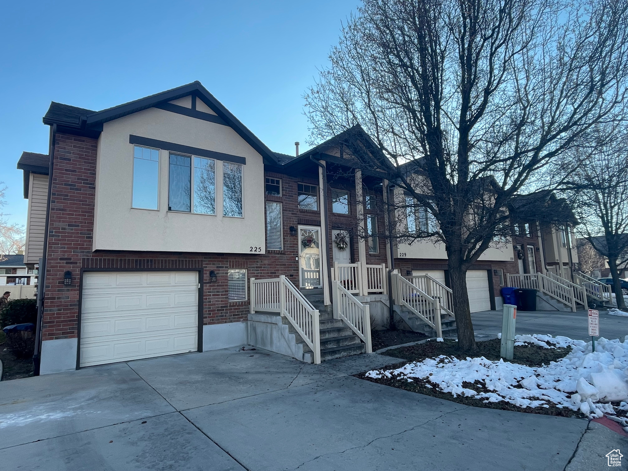 Split foyer home with brick siding, stucco siding, an attached garage, and concrete driveway