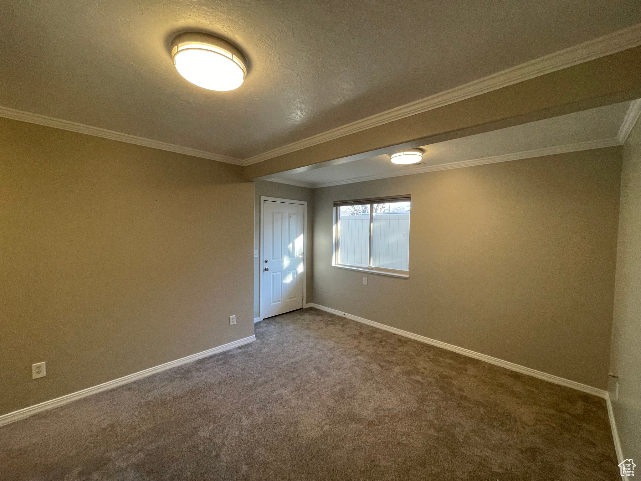 Carpeted family room with a textured ceiling, baseboards, and walkout to south-facing patio