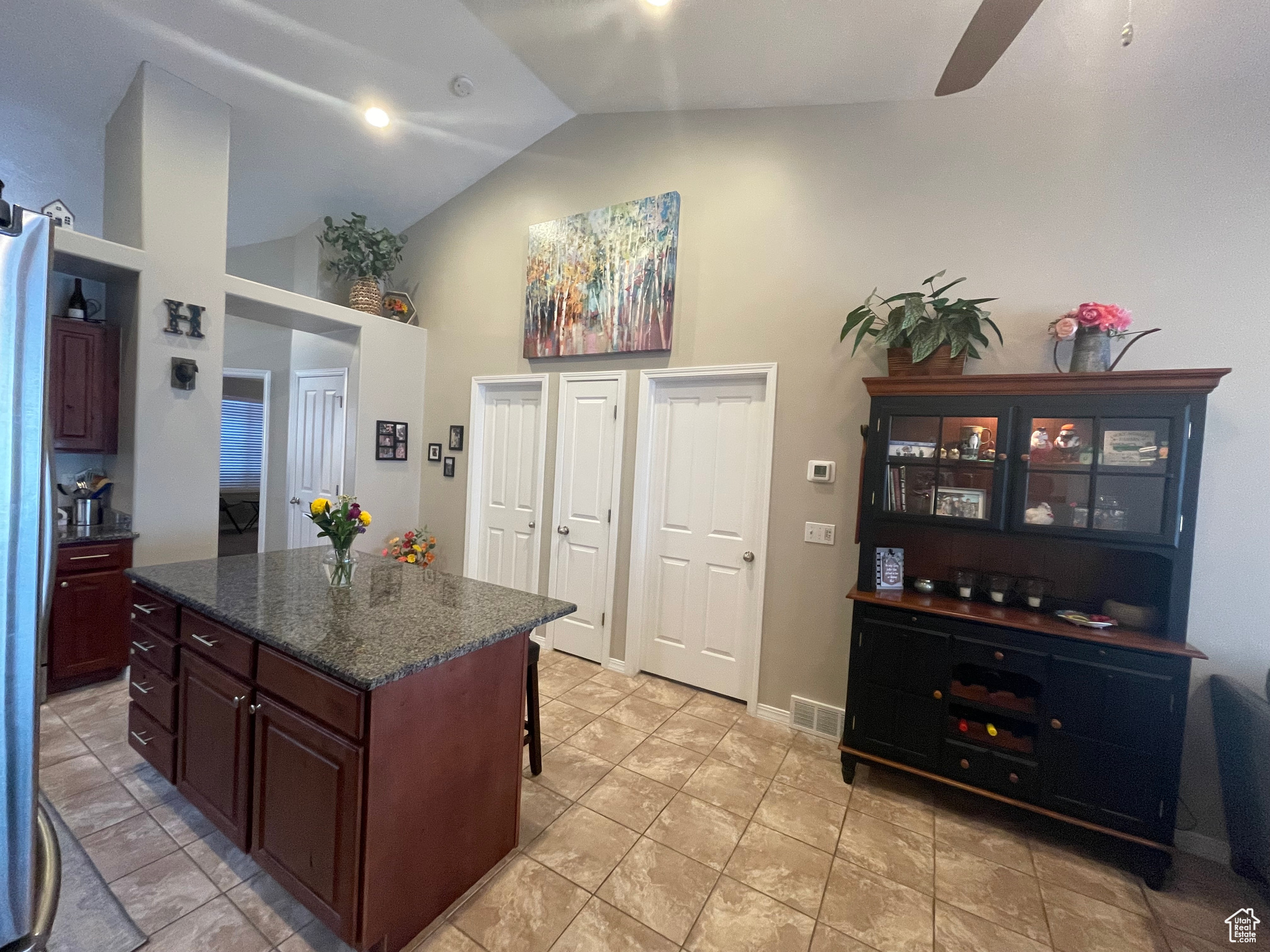 Kitchen with large island, ceiling fan, dark stone counters, and a breakfast bar