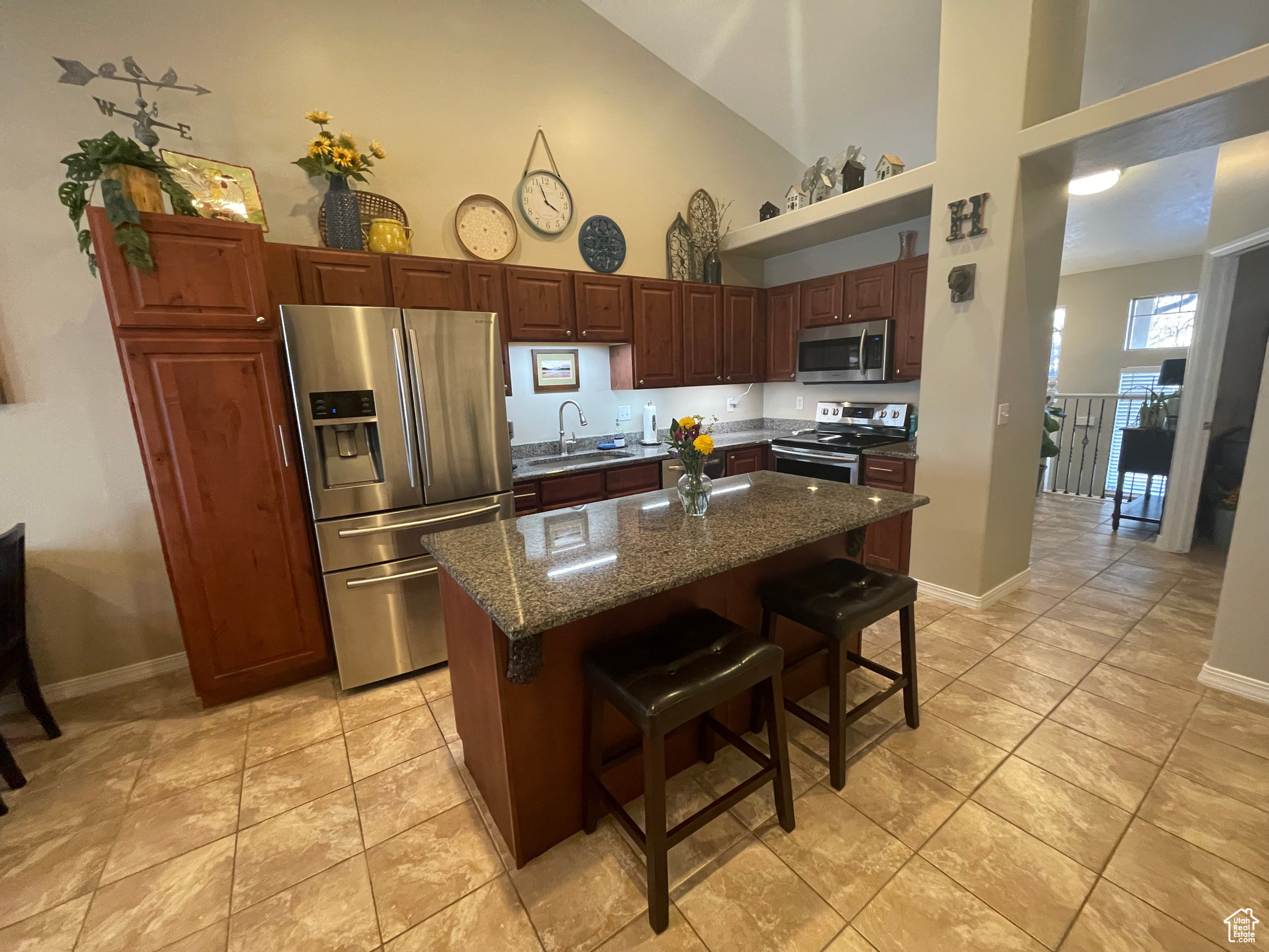 Kitchen featuring high vaulted ceiling, a breakfast bar, sink, stainless steel appliances, and large center island