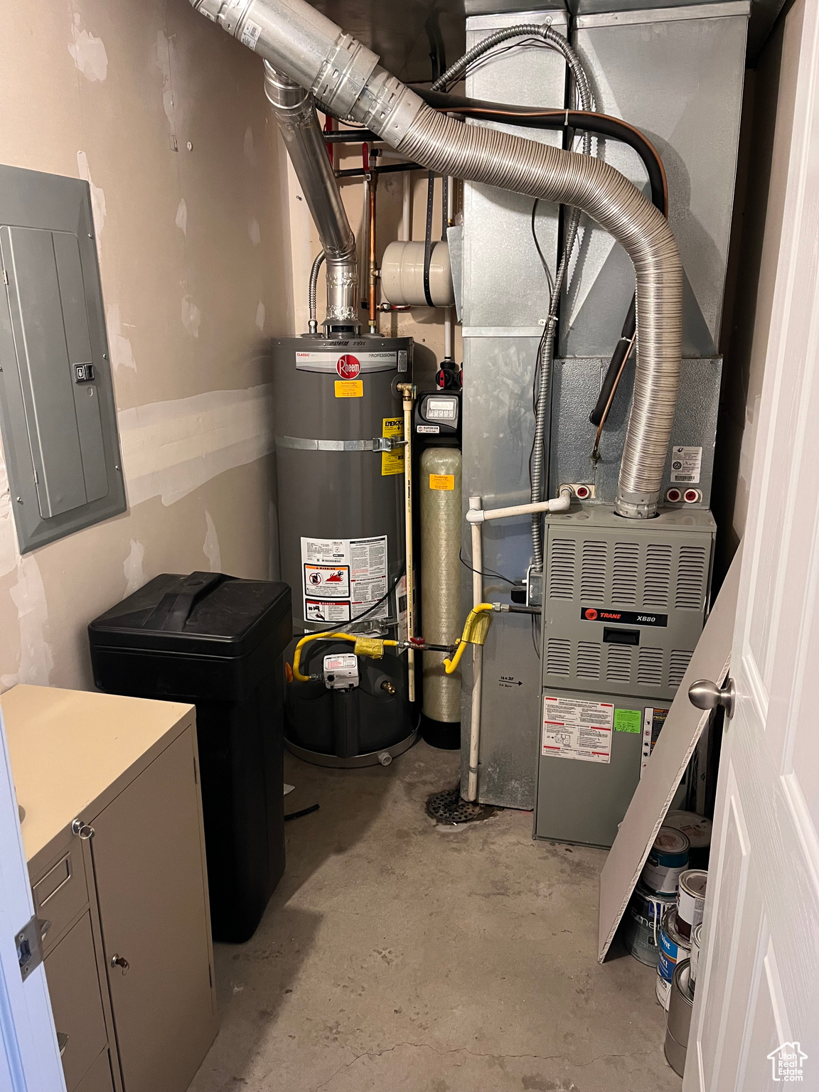 Utility room with electric panel, brand new strapped water heater, water softener, and heating unit