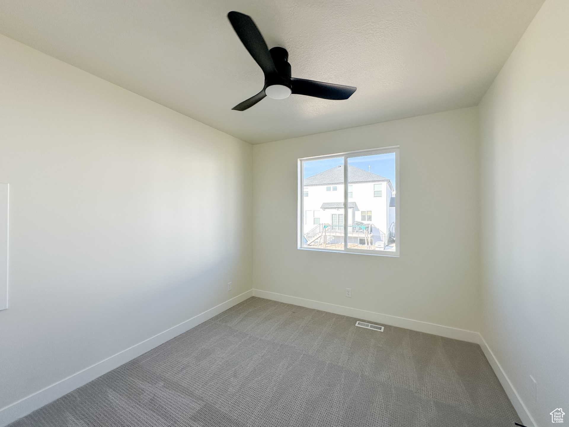 Empty room featuring baseboards, carpet floors, visible vents, and ceiling fan