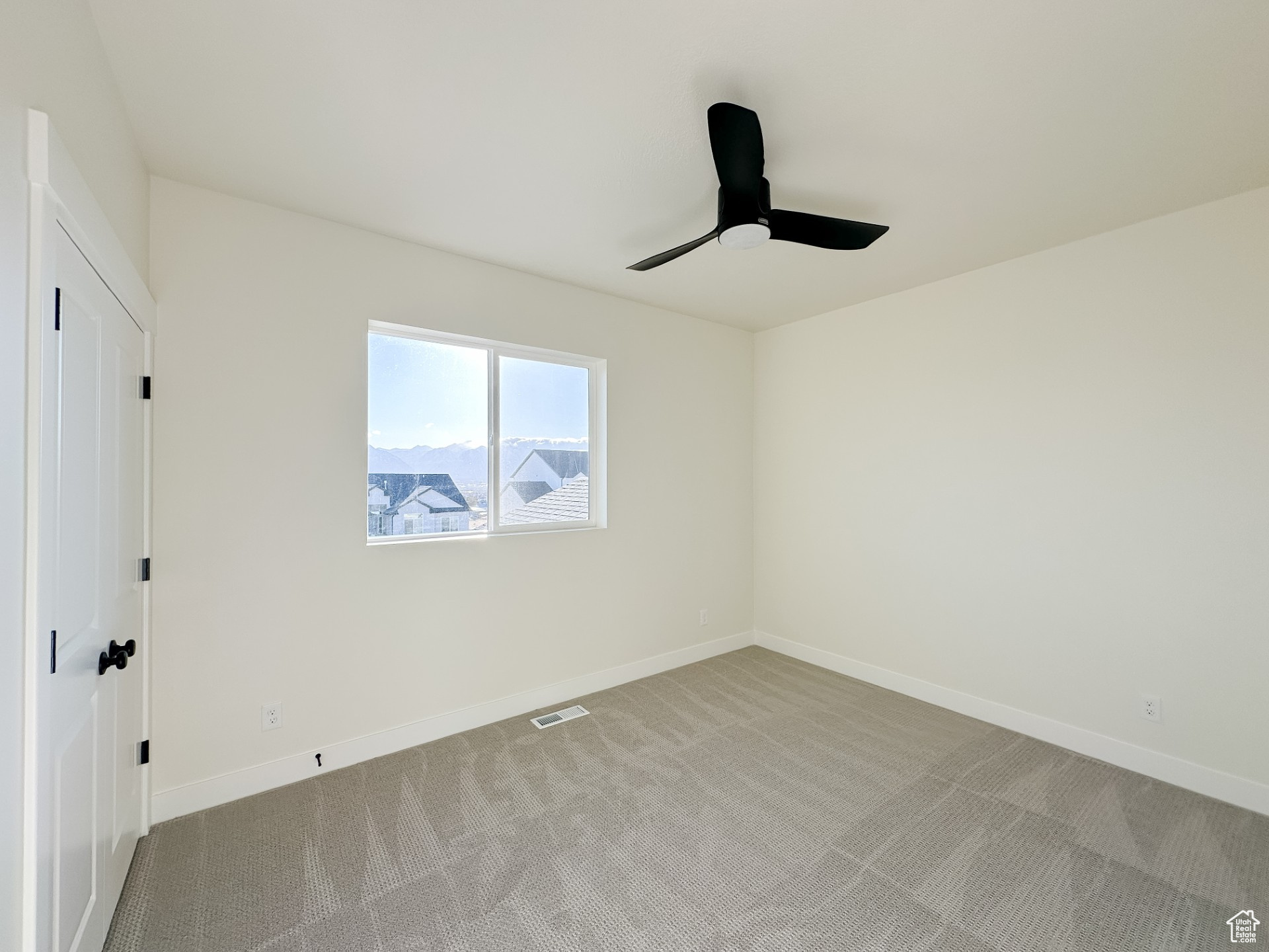 Carpeted empty room with baseboards, visible vents, and ceiling fan