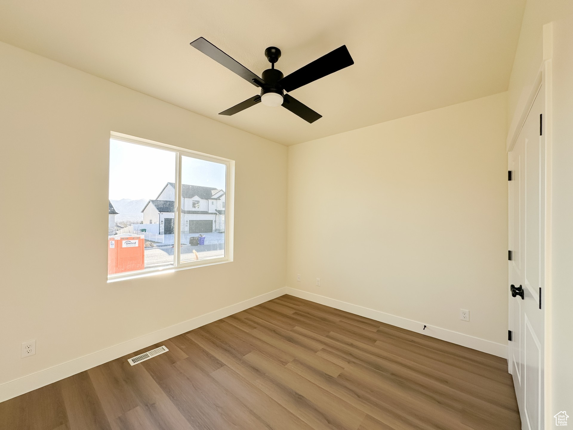 Unfurnished room featuring visible vents, a ceiling fan, baseboards, and wood finished floors