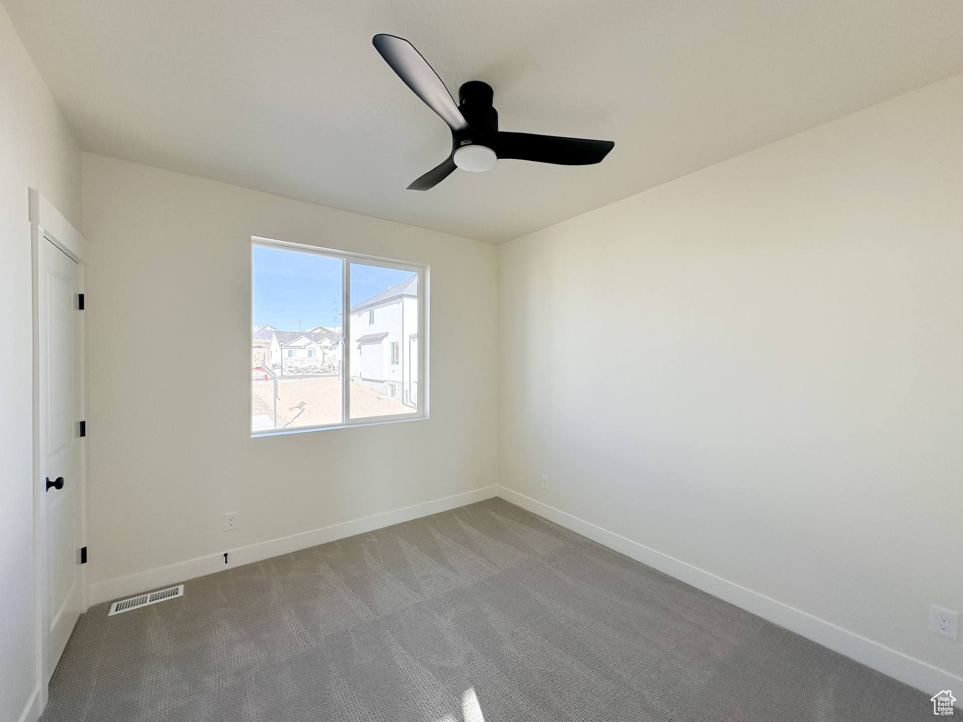 Carpeted spare room featuring visible vents, baseboards, and a ceiling fan