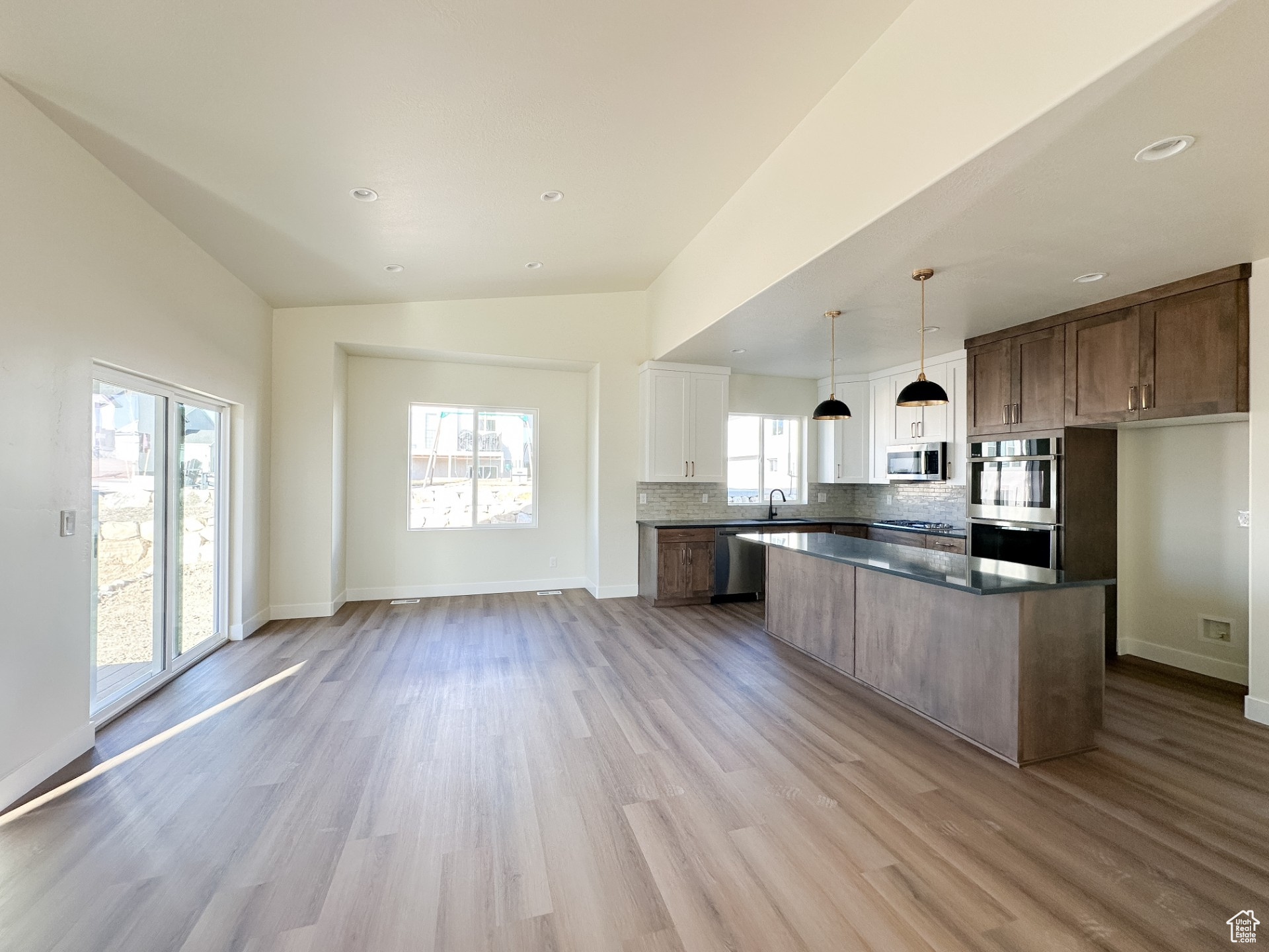 Kitchen with stainless steel appliances, plenty of natural light, backsplash, and light wood finished floors