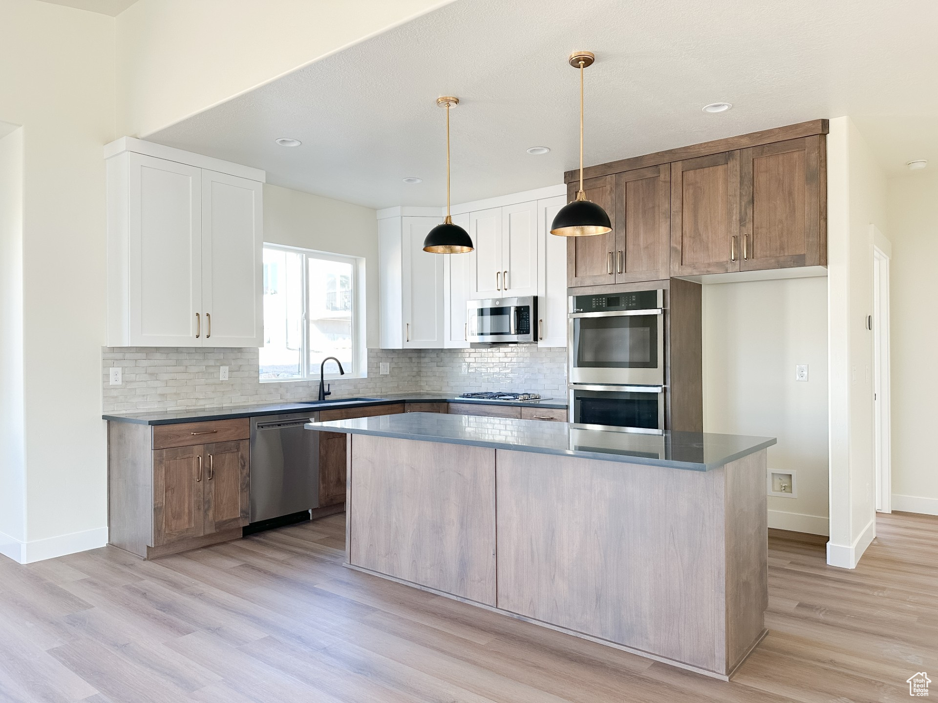Kitchen with tasteful backsplash, a center island, light wood-style flooring, stainless steel appliances, and a sink
