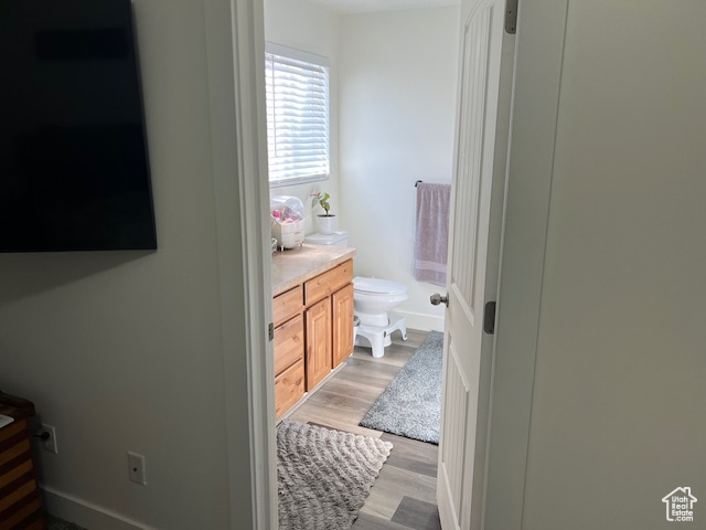 Bathroom with toilet, vanity, and wood finished floors