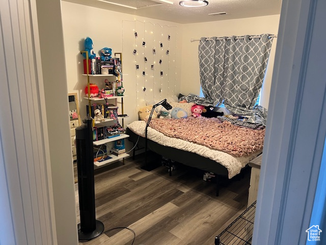 Bedroom featuring visible vents, a textured ceiling, and wood finished floors