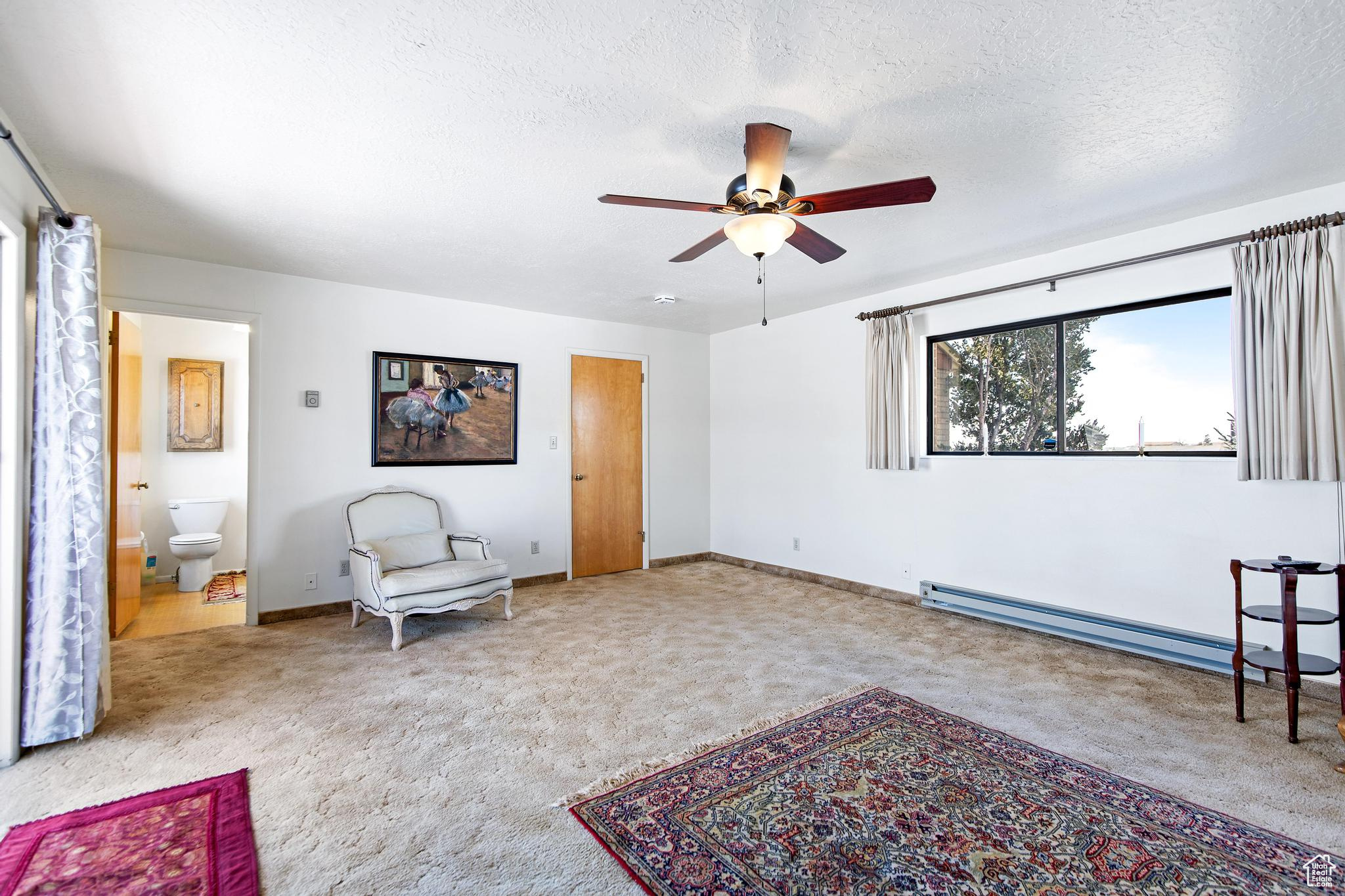 Sitting room featuring a baseboard heating unit, carpet floors, a textured ceiling, and baseboards
