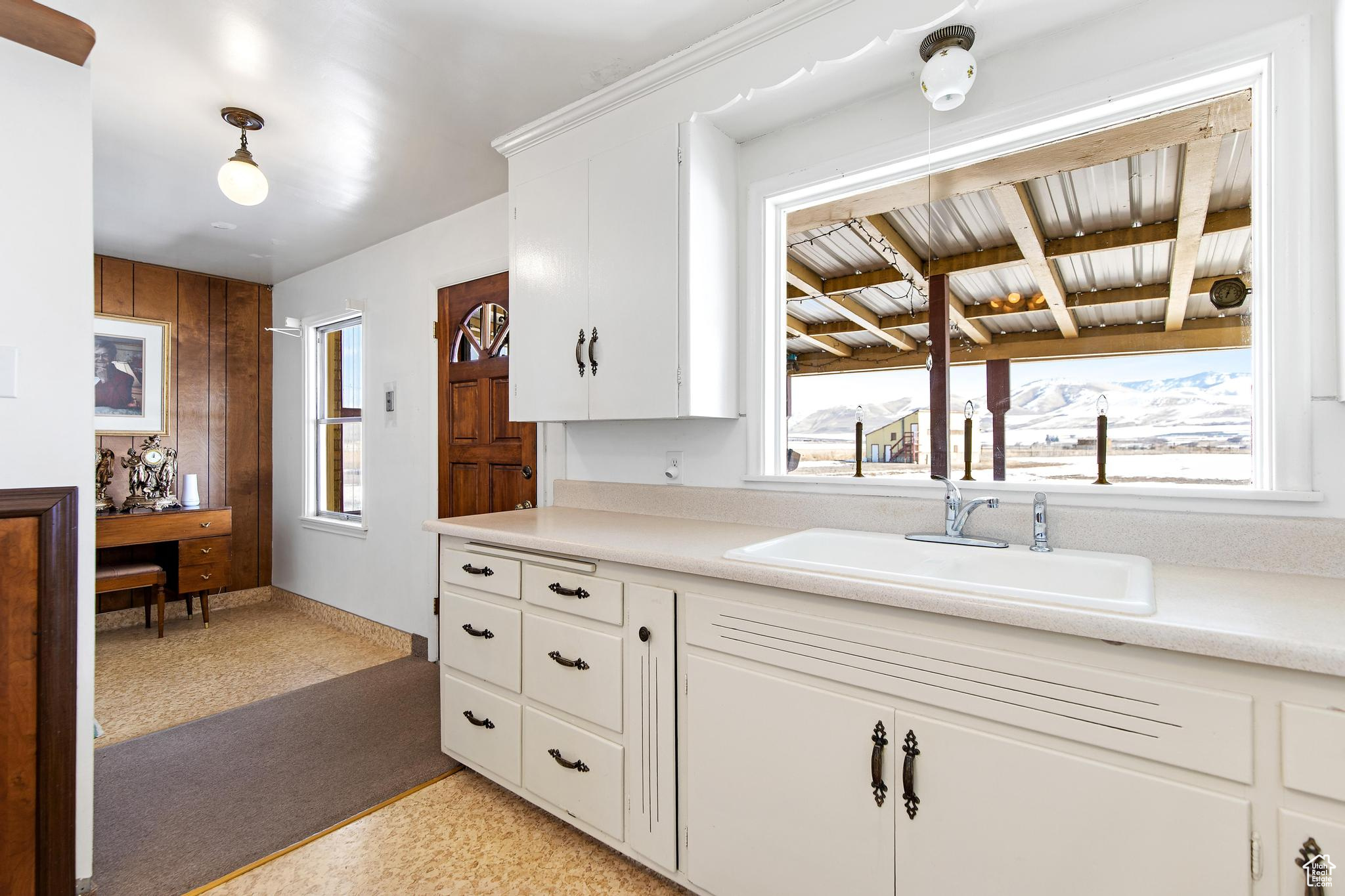 Kitchen featuring a sink, white cabinets, and light countertops
