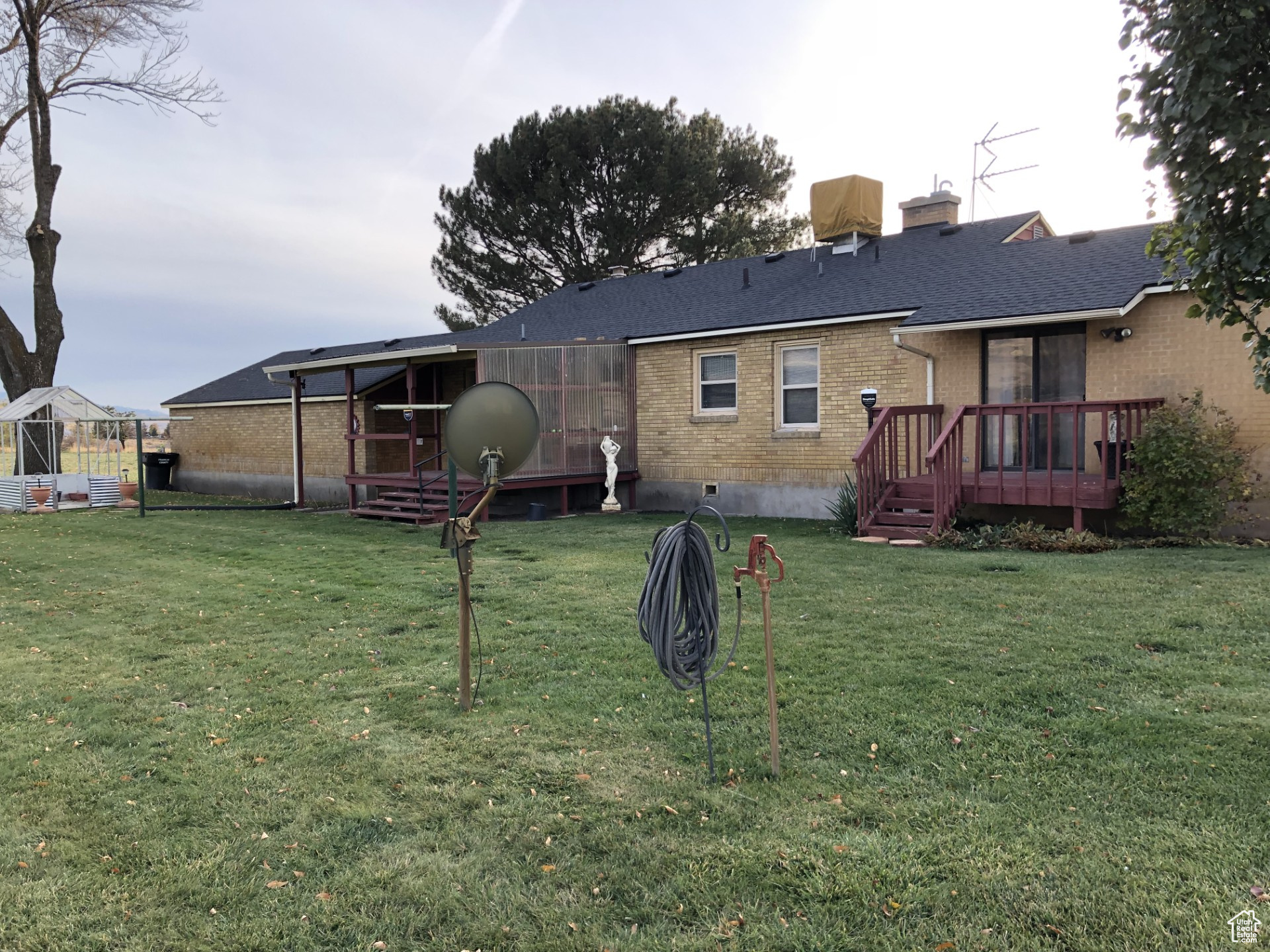Rear view of property with a lawn, brick siding, roof with shingles, and crawl space