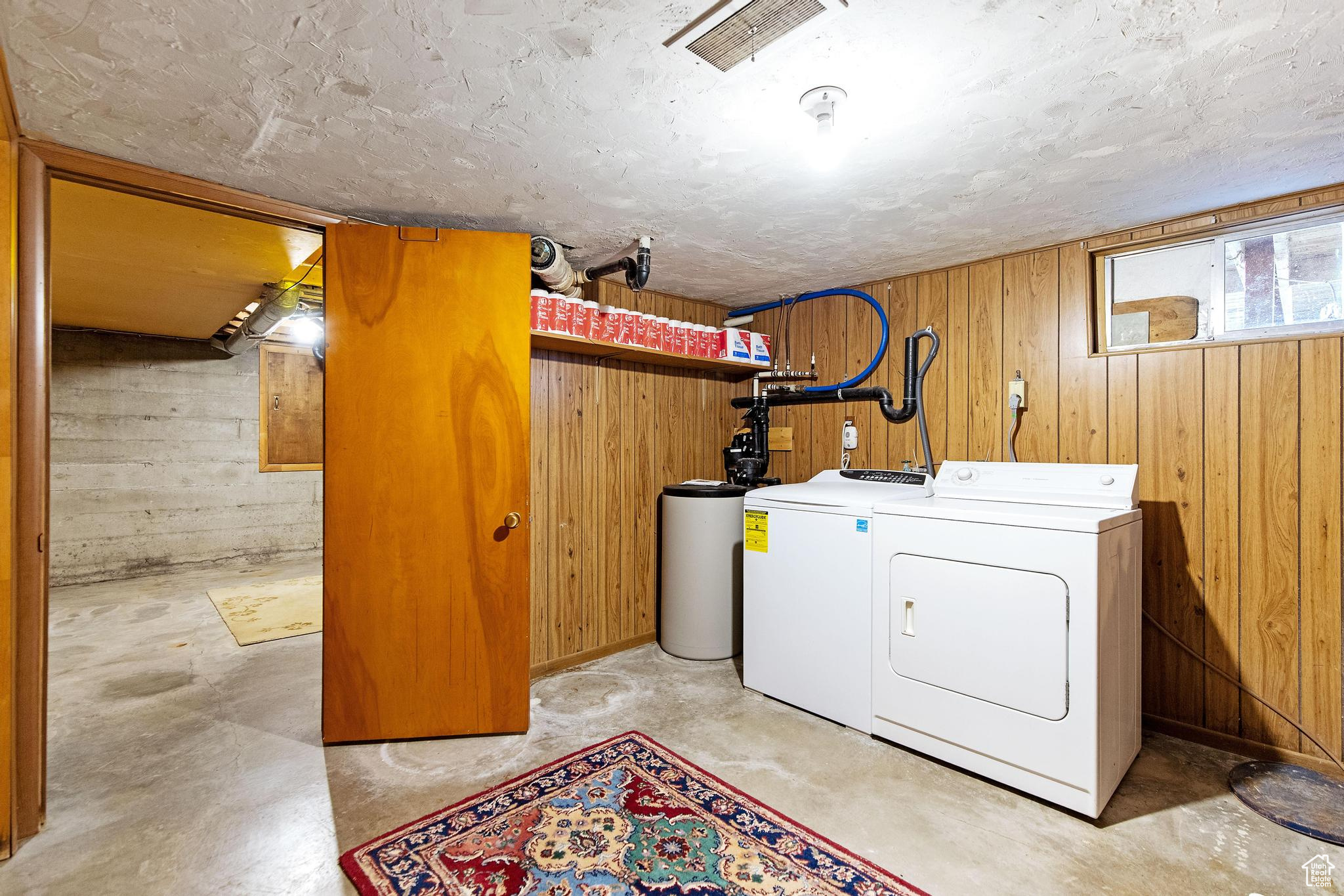 Washroom with separate washer and dryer, wooden walls, and laundry area