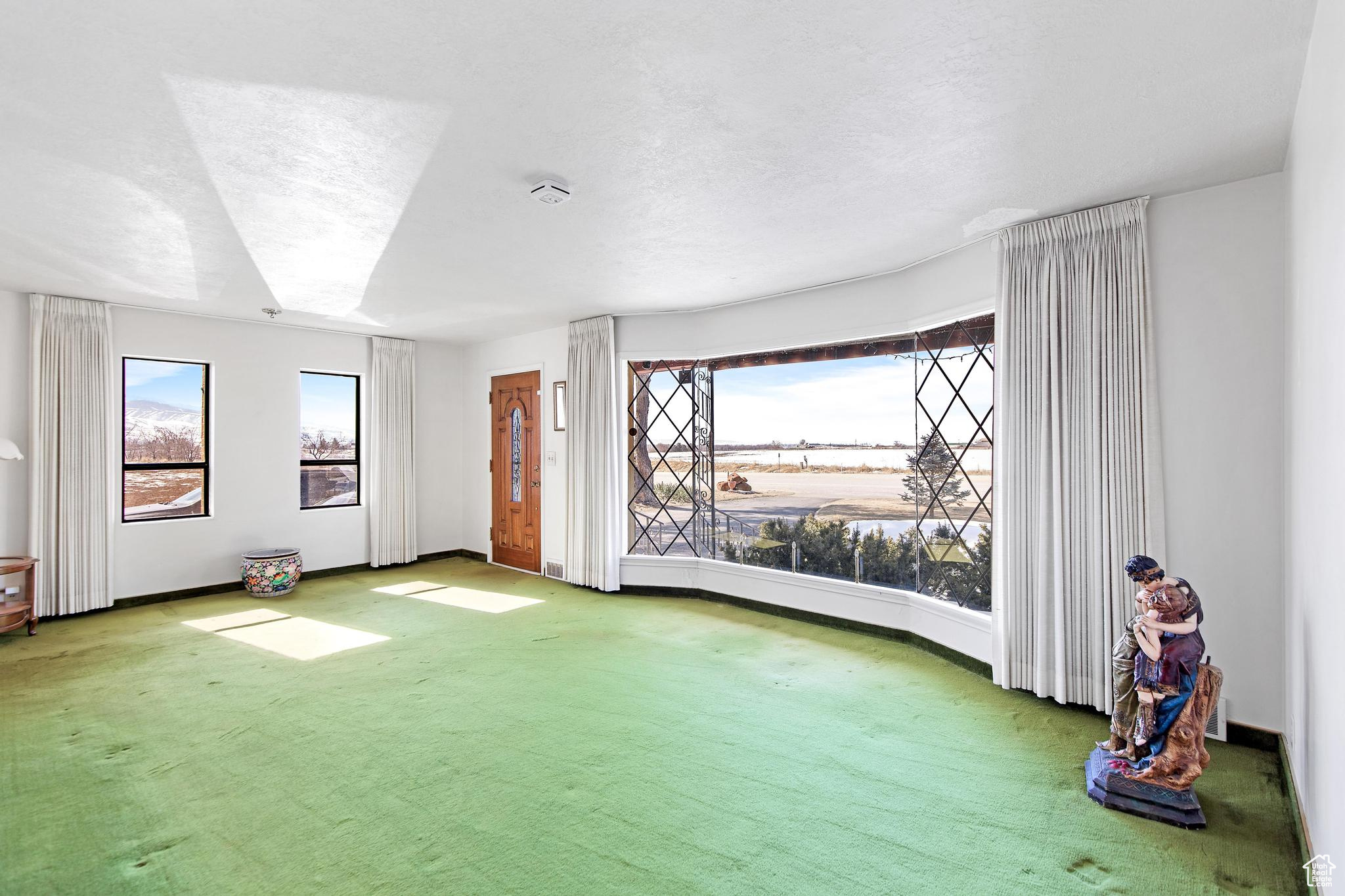 Carpeted empty room with a textured ceiling and baseboards