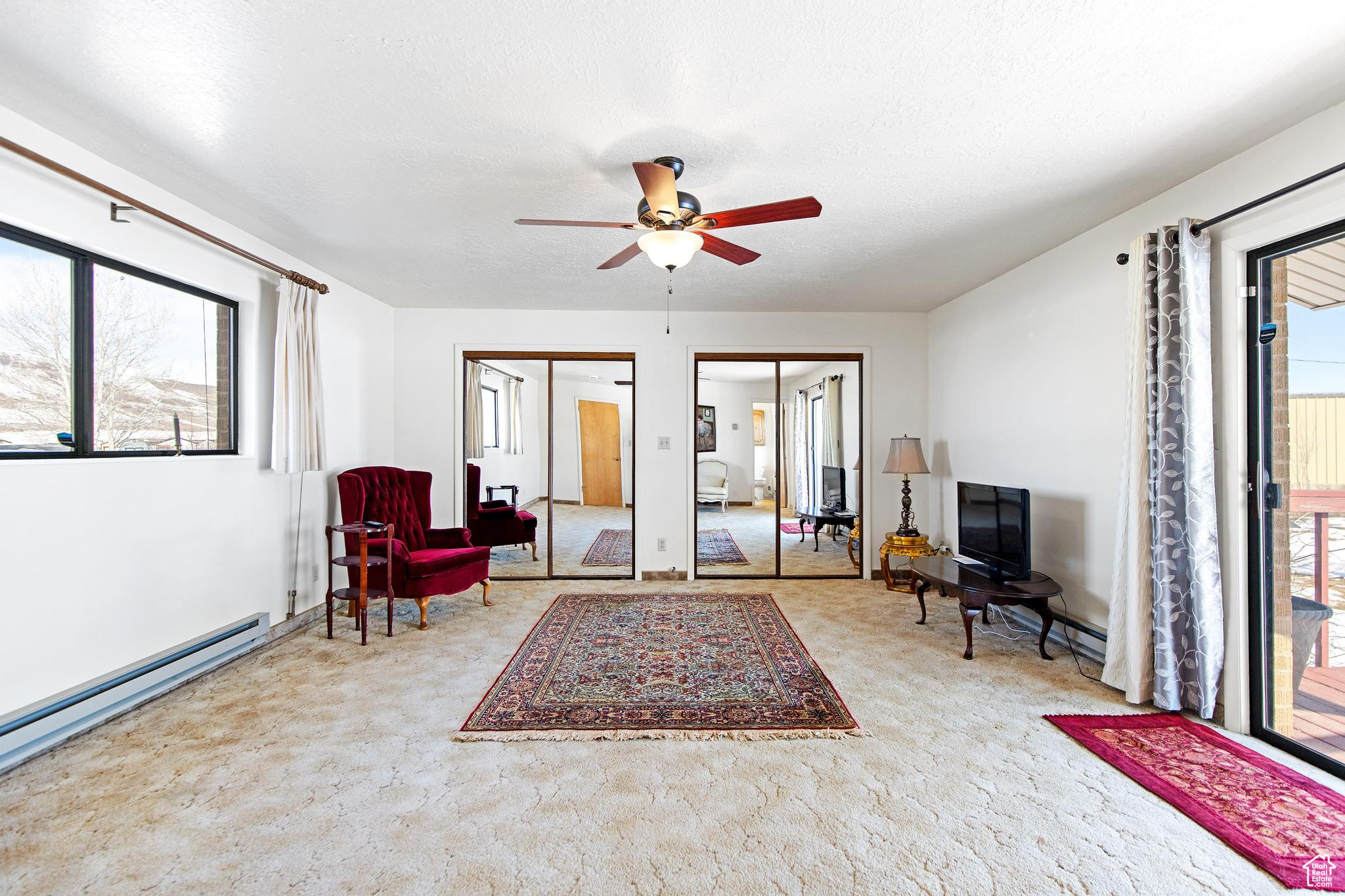 Living area featuring baseboard heating, plenty of natural light, and a textured ceiling
