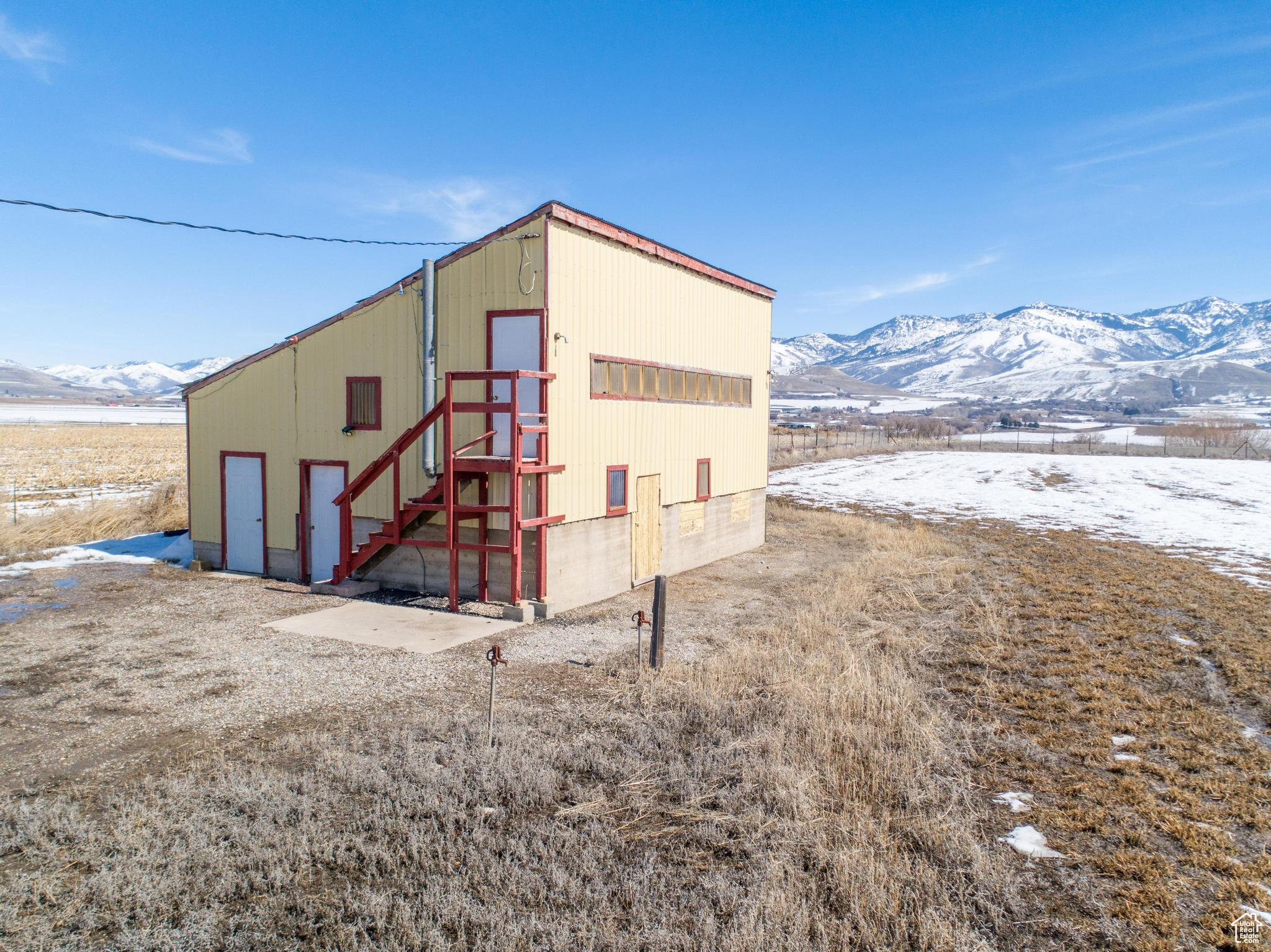 Snow covered structure with an outbuilding, a mountain view, and an outdoor structure