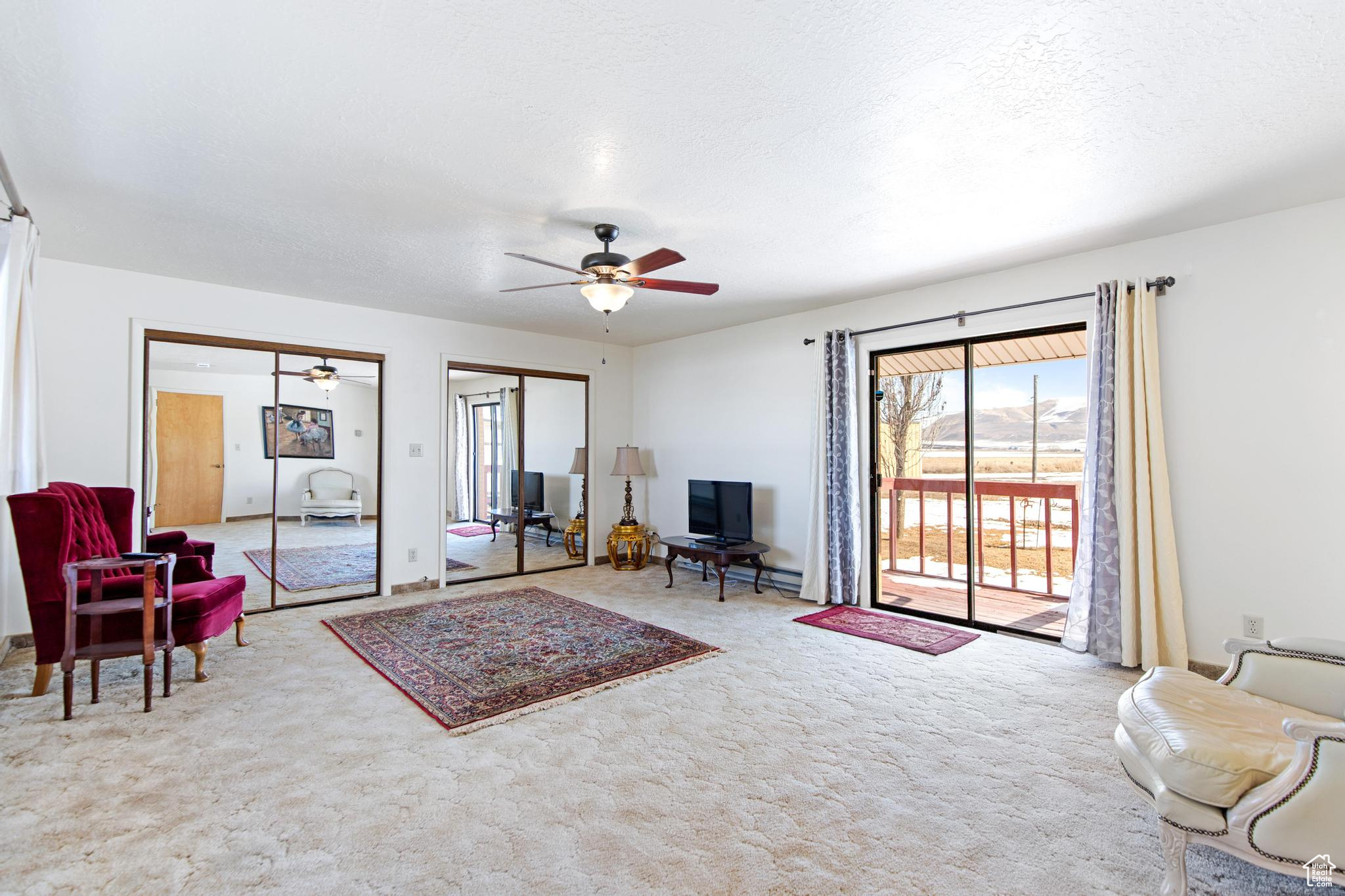 Living room with ceiling fan, carpet flooring, and a textured ceiling