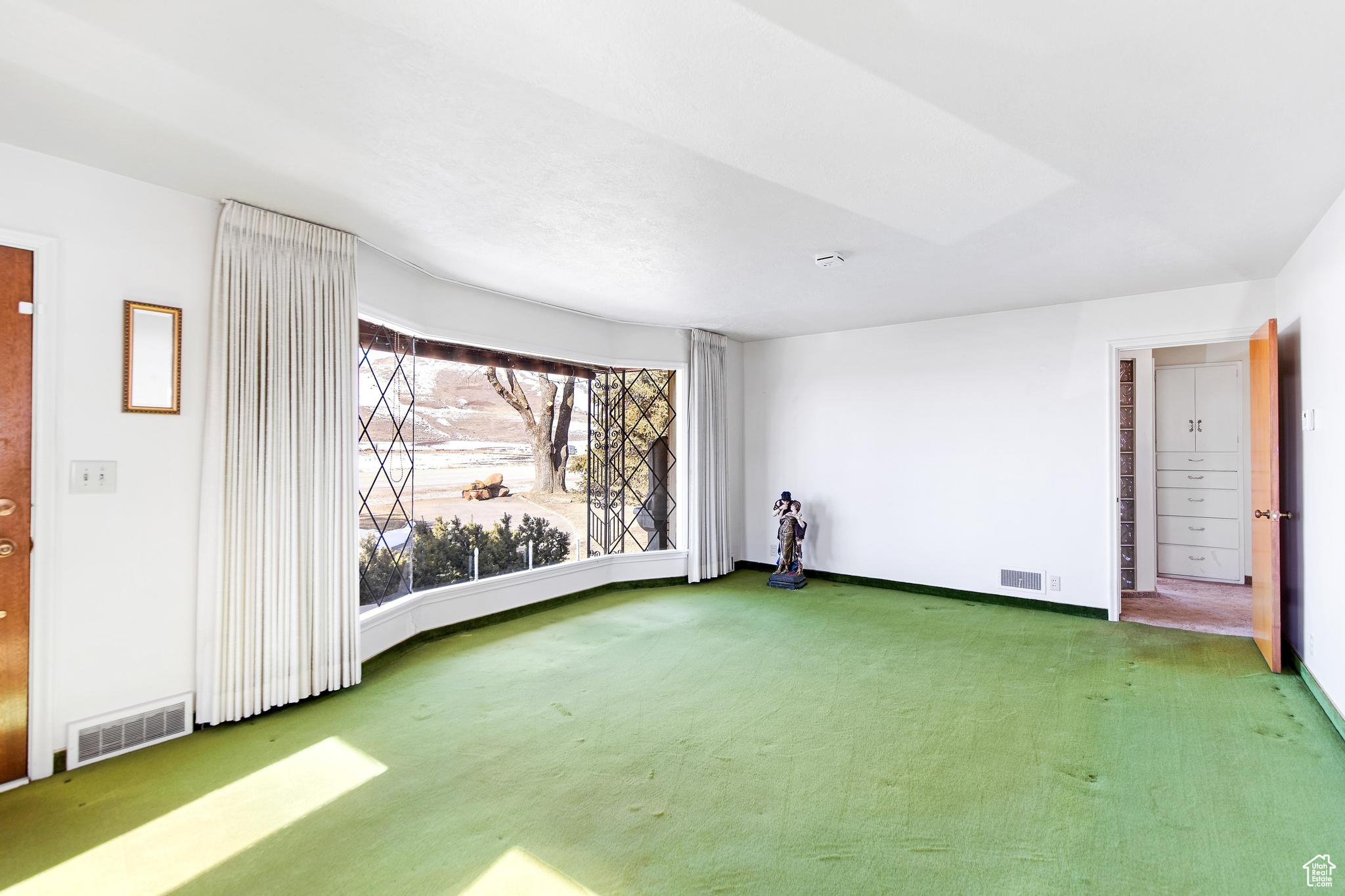 Carpeted empty room featuring baseboards and visible vents