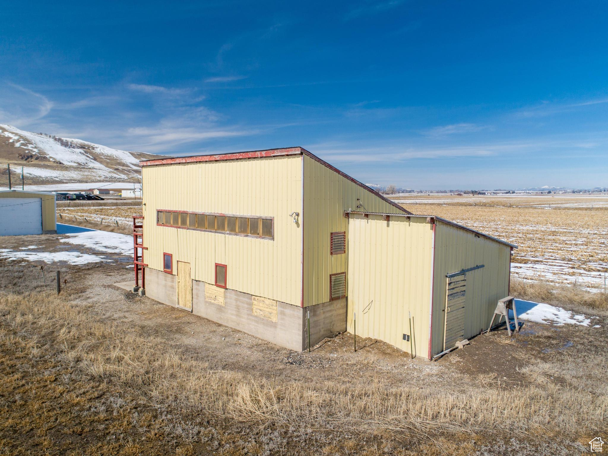 Snow covered structure with an outbuilding and a pole building